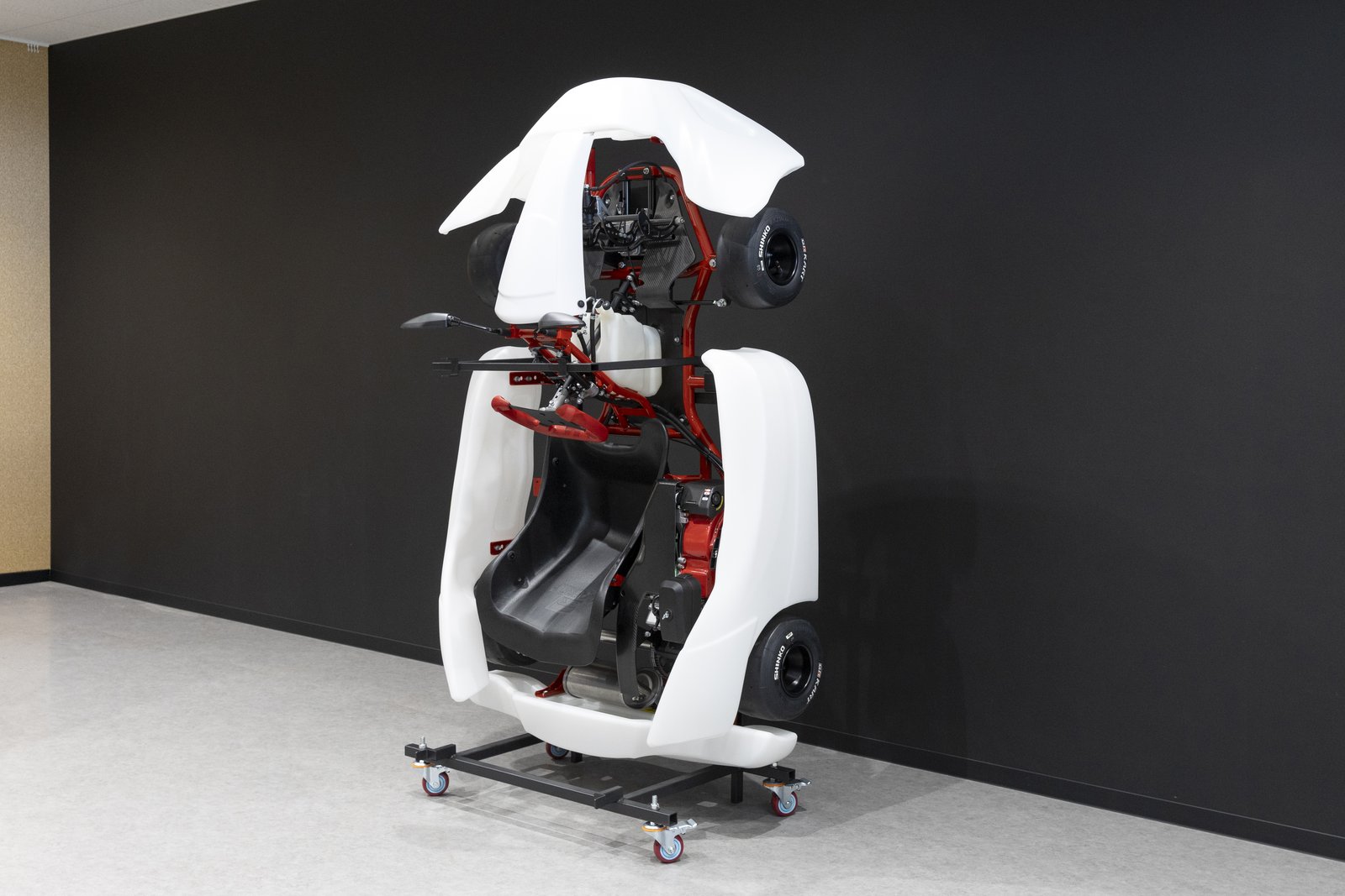 Toyota GR Kart stored upright on a wheeled stand against a wall