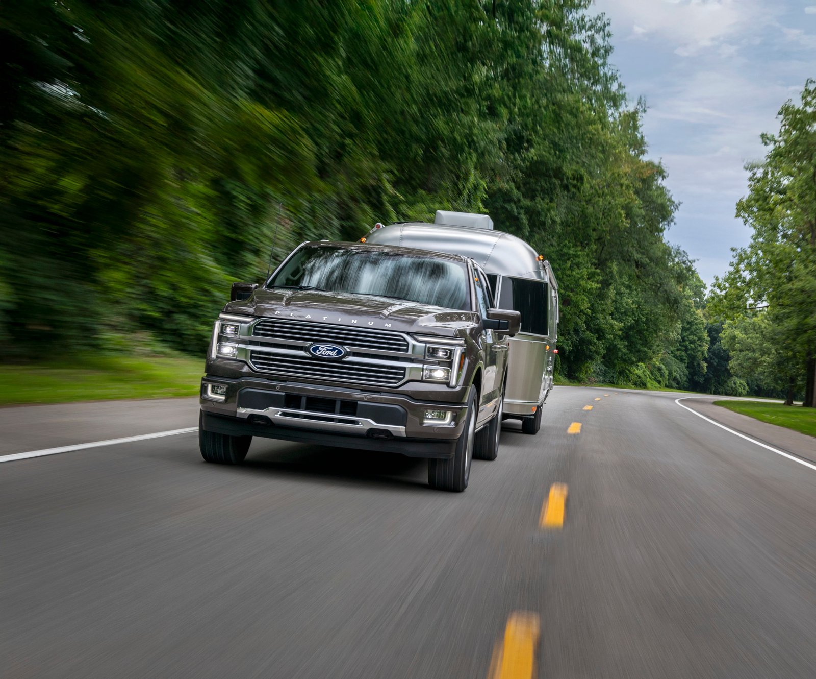 2026 Ford F-150 Platinum towing a travel trailer on a two-lane road