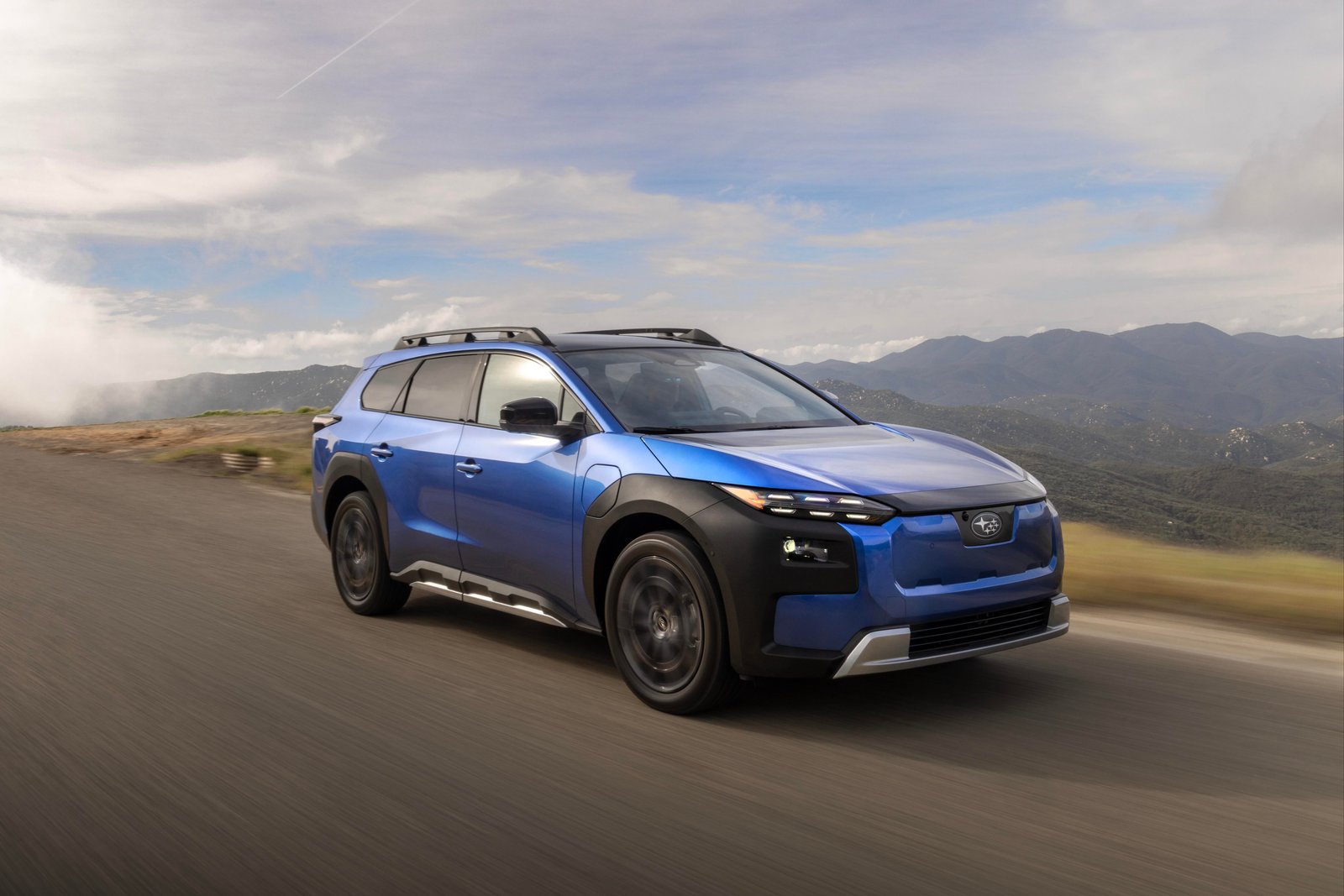 Blue 2026 Subaru Trailseeker EV driving on a mountain road