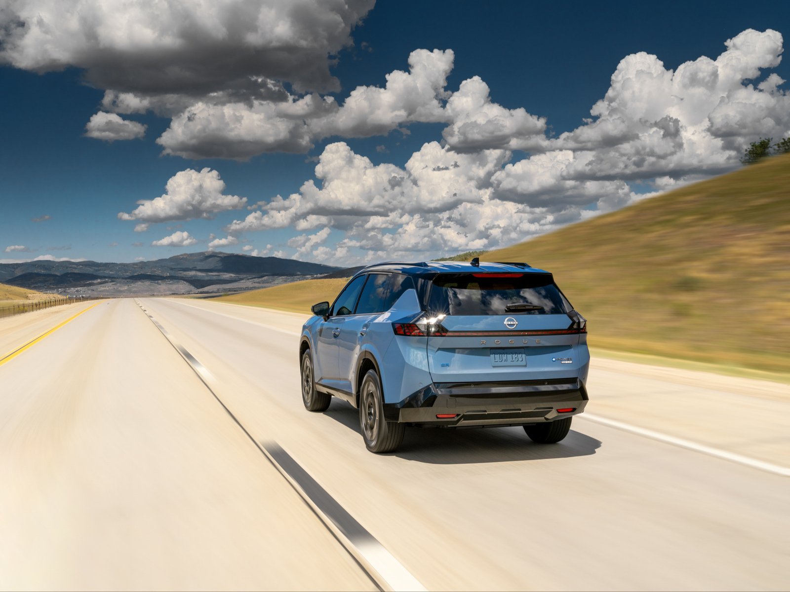 2027 Nissan Rogue Hybrid rear view driving on highway