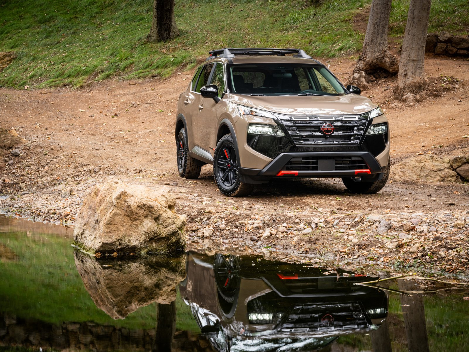 2027 Nissan Rogue Rock Creek front three-quarter view parked by a creek