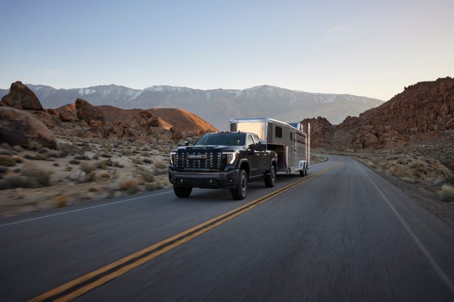 2027 GMC Sierra HD Denali Ultimate towing a horse trailer on a desert highway
