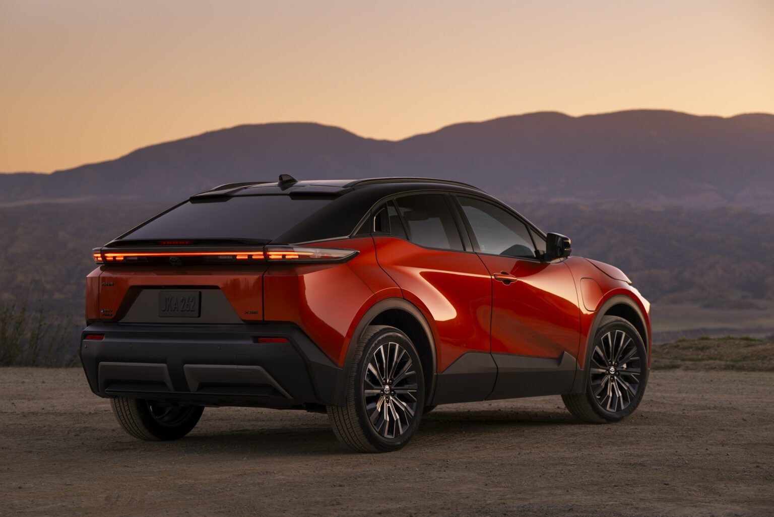 2027 Toyota C-HR XSE in orange, rear three-quarter view at sunset