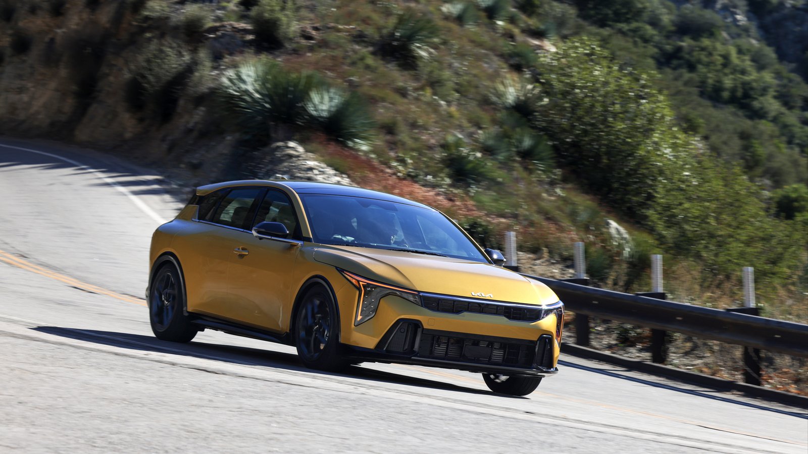 Yellow 2026 Kia K4 Hatchback cornering on a mountain road