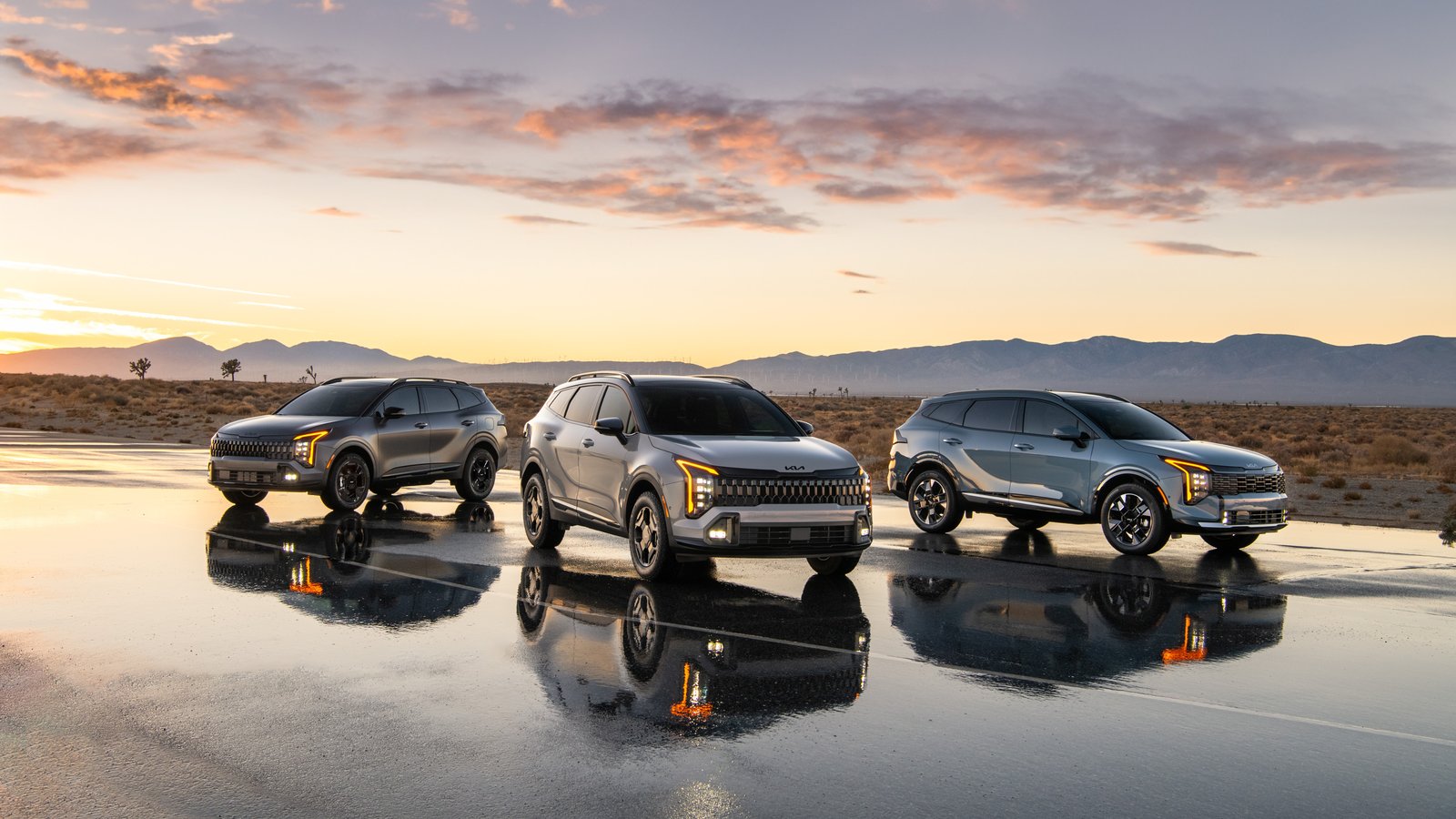 Three 2027 Kia Sportage models parked on wet pavement at sunset