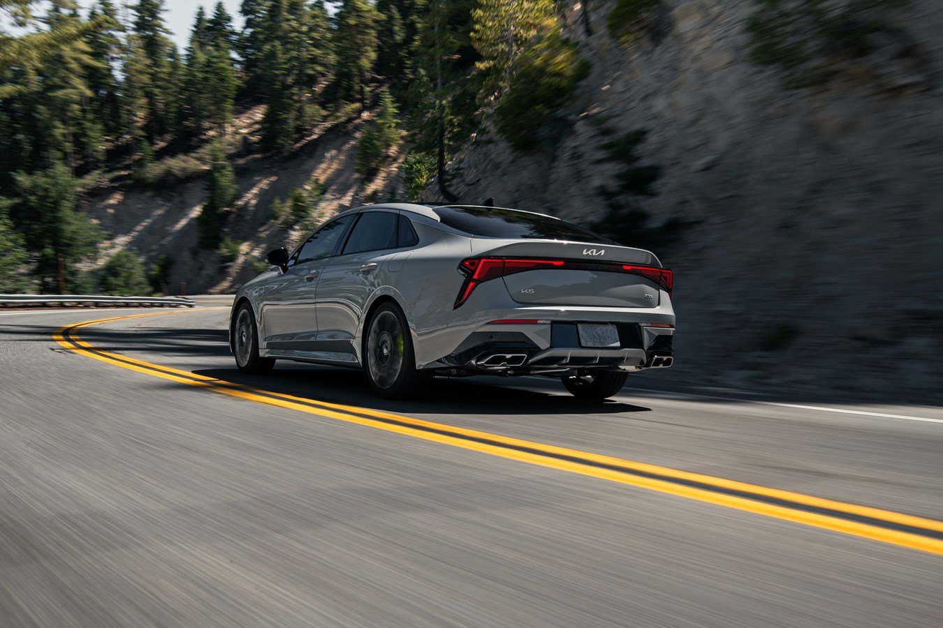 2027 Kia K5 rear view on a winding road