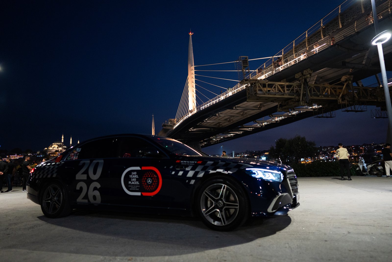 Dark blue Mercedes S-Class parked under Istanbul's Golden Horn bridge at night