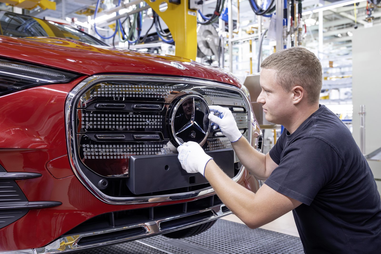 Worker fitting the star emblem to a red Mercedes GLA grille