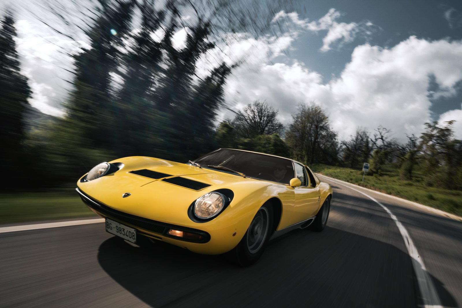 Yellow Lamborghini Miura SV driving on a country road