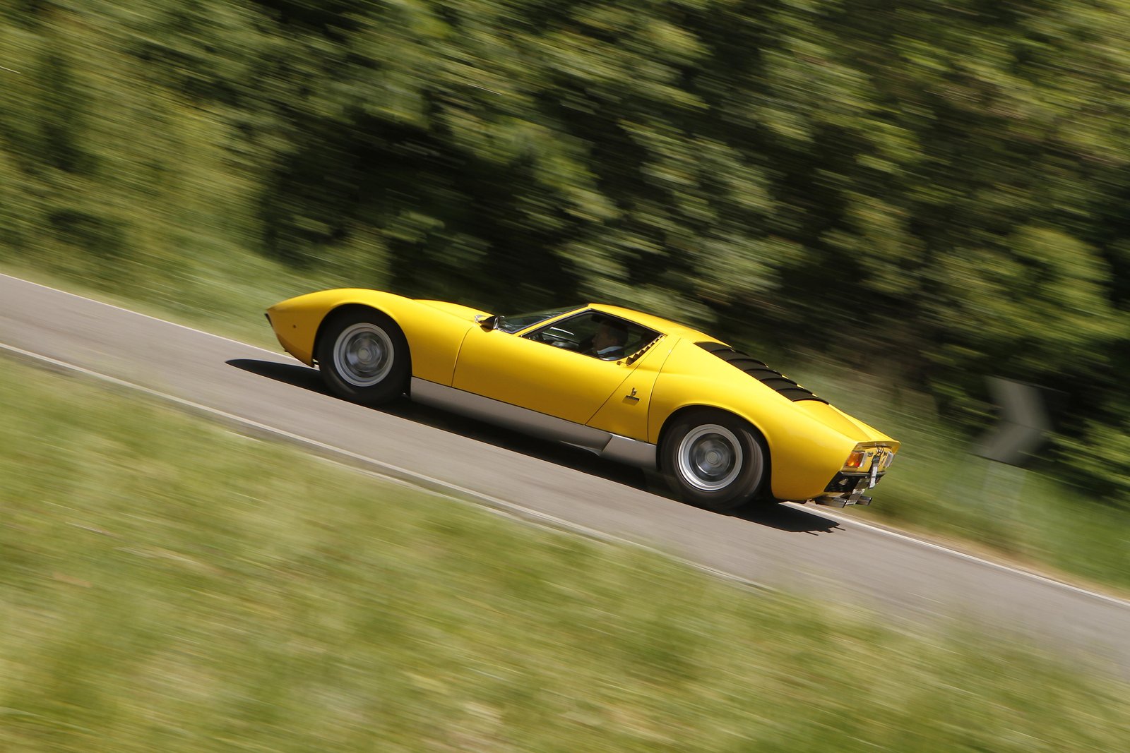 Yellow Lamborghini Miura SV driving on a country road