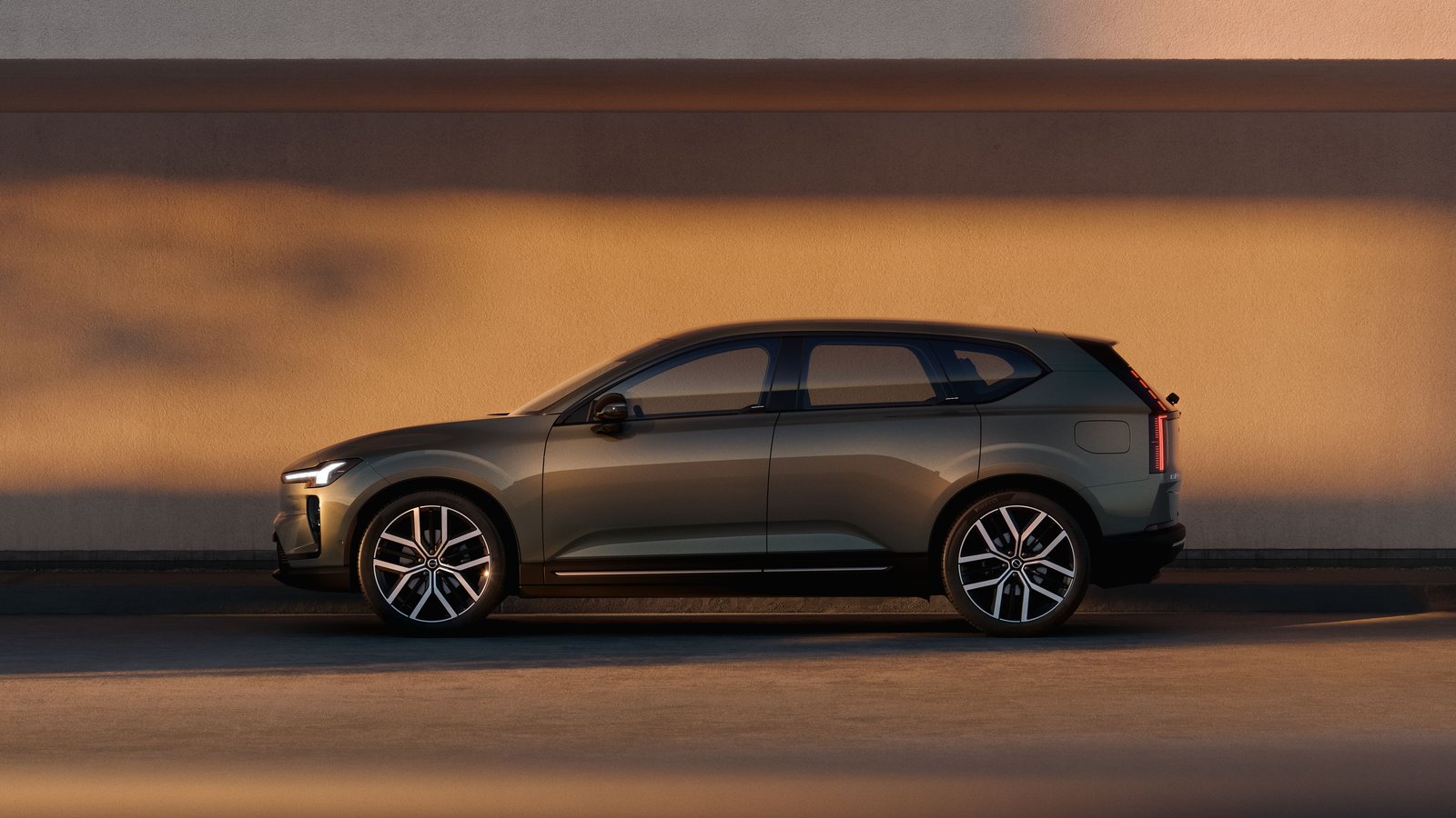 Volvo EX60 electric SUV in profile against a sunlit concrete wall