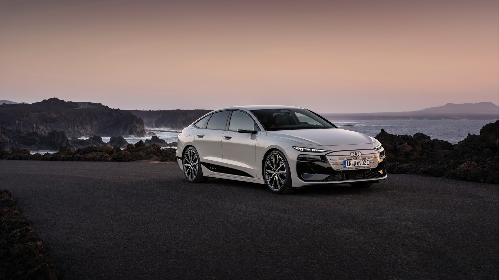White Audi A6 Sportback e-tron parked on a coastal road at dusk