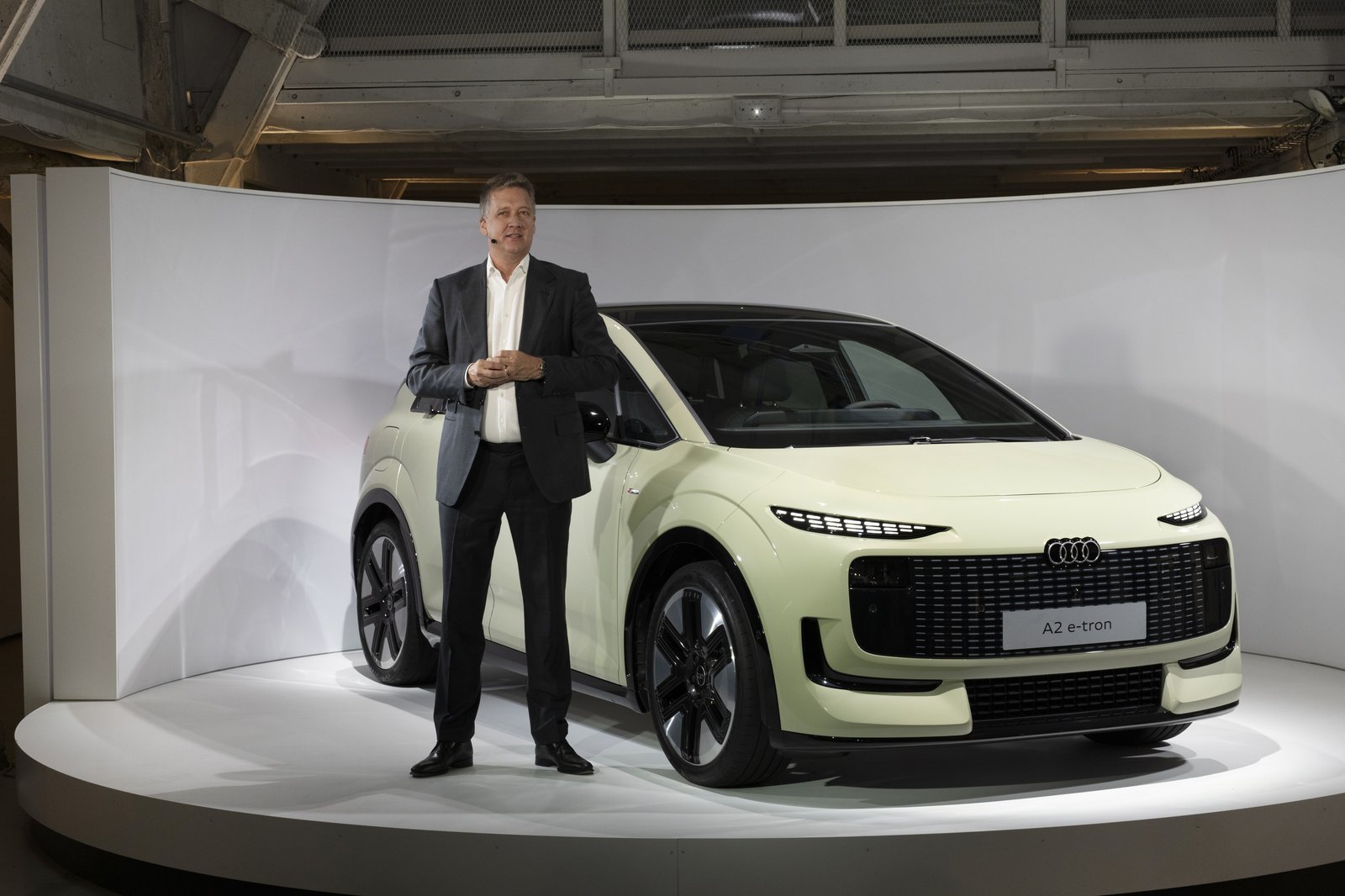 Audi CEO Gernot Döllner stands beside the A2 e-tron on stage