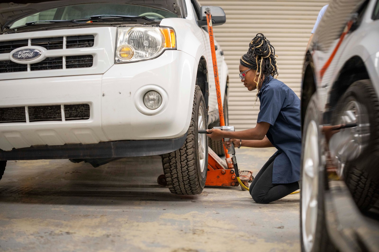 Student uses an impact wrench on a Ford Escape's front wheel