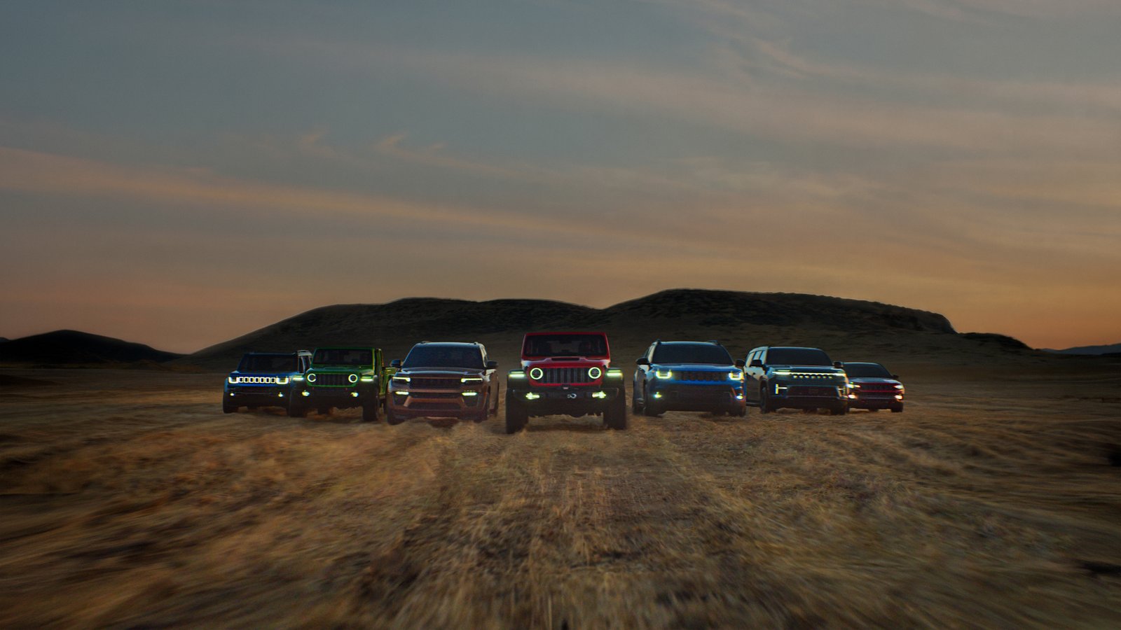 Seven Jeep models lined up in desert at dusk