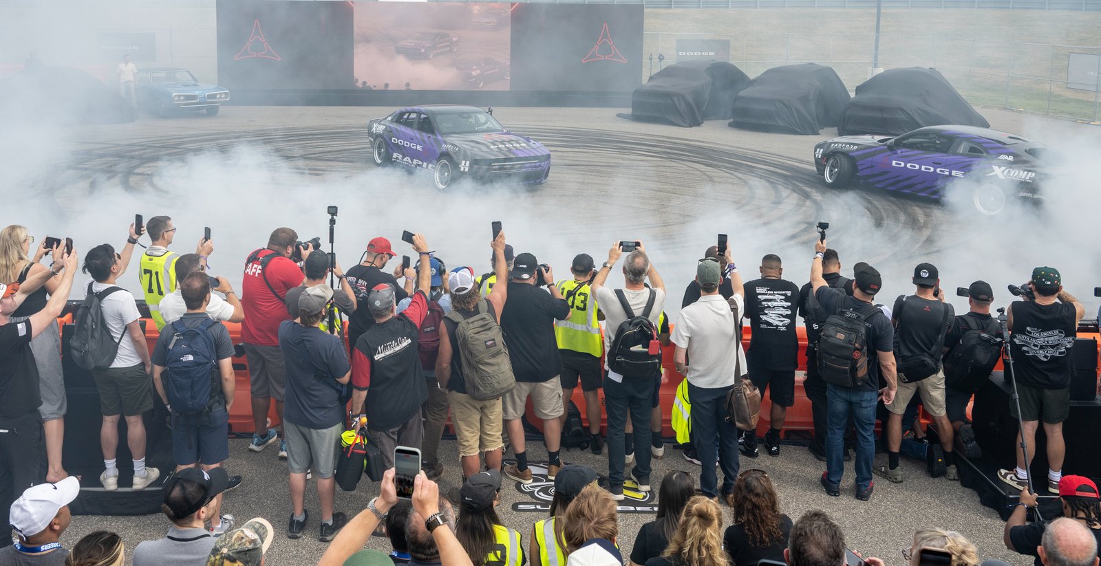 Crowd watching Dodge Charger drift cars perform donuts