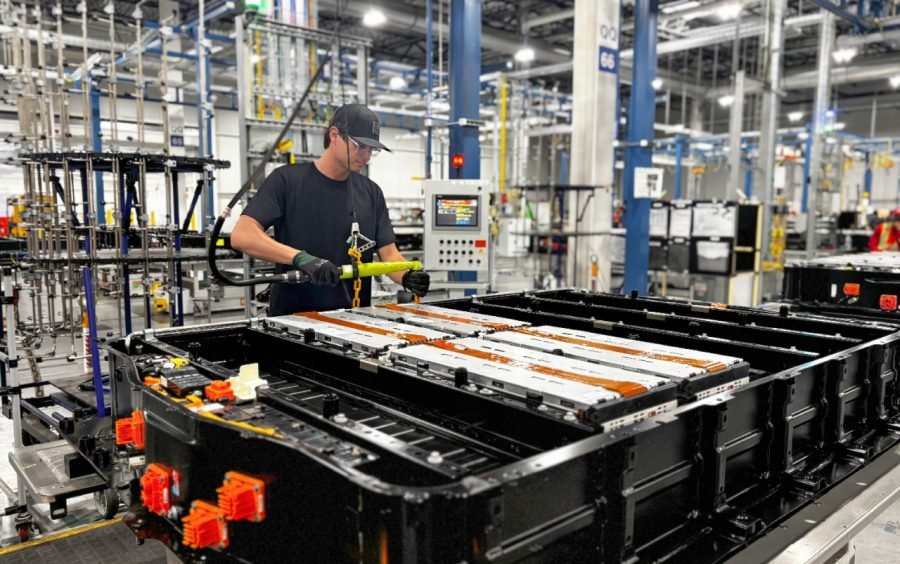 Worker assembling an EV battery pack with installed modules