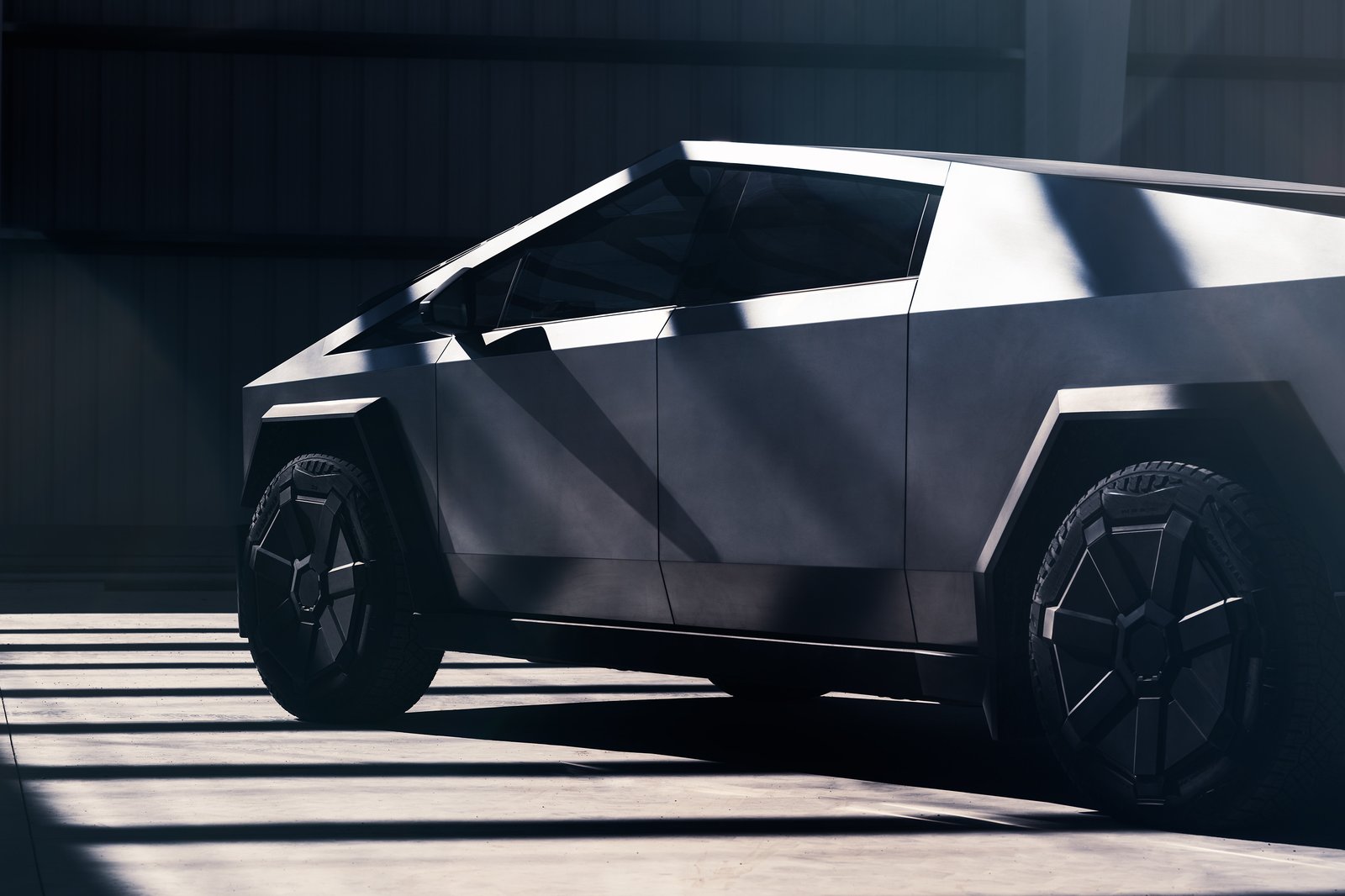 Tesla Cybertruck parked inside a hangar with light falling across the body