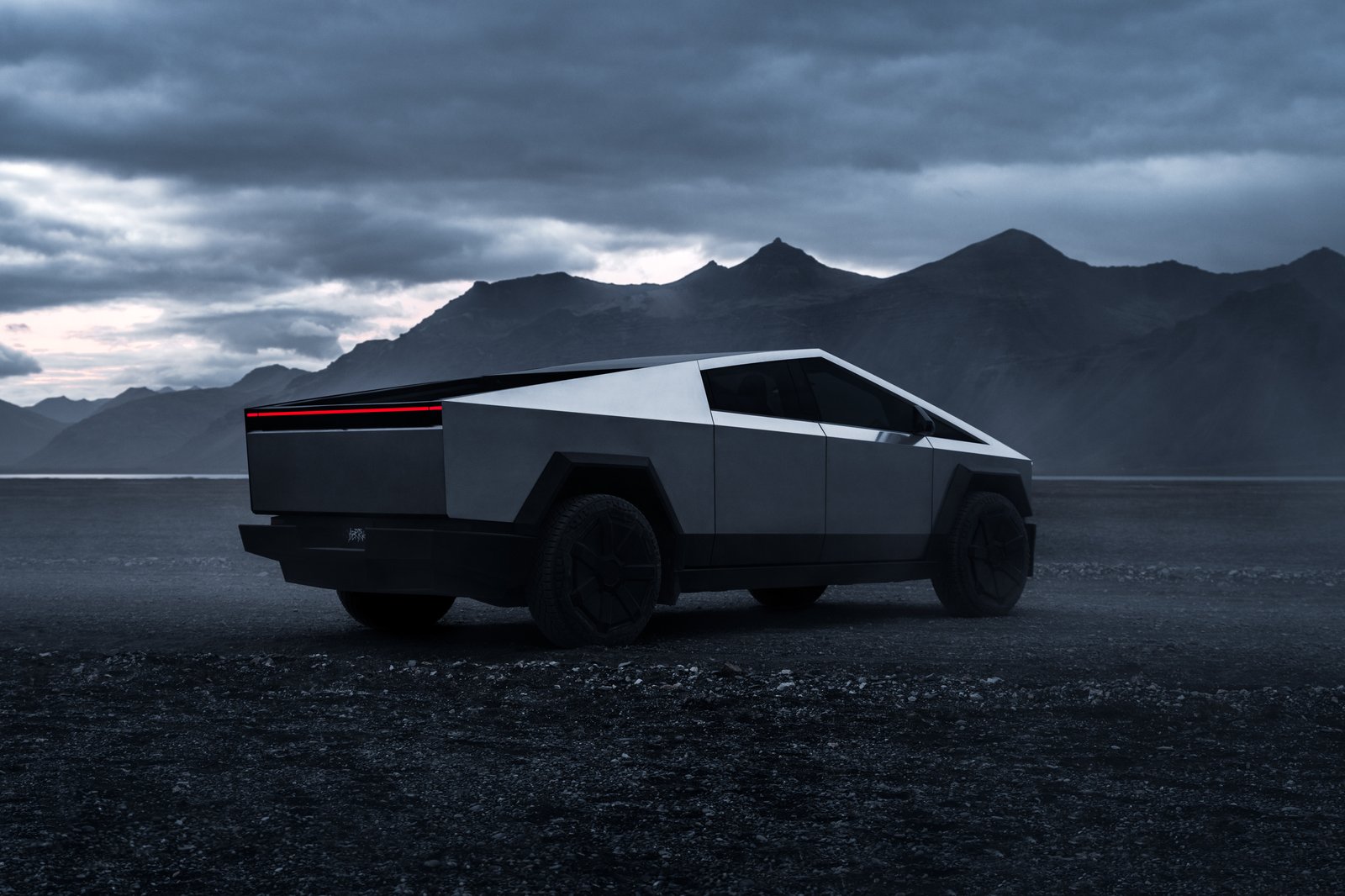 Tesla Cybertruck rear three-quarter view with the full-width taillight lit