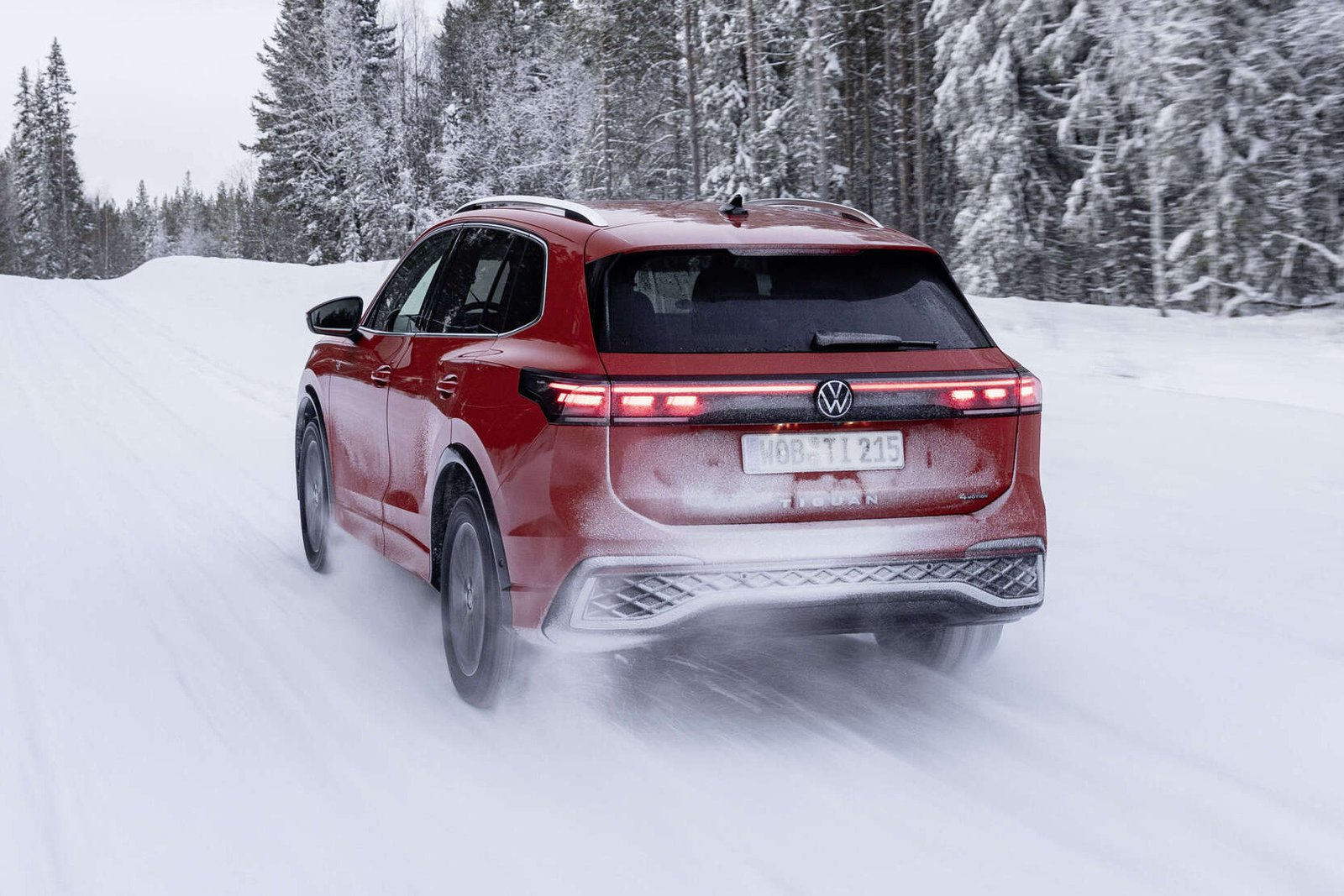 Rear view of red Volkswagen Tiguan with taillights on in snow