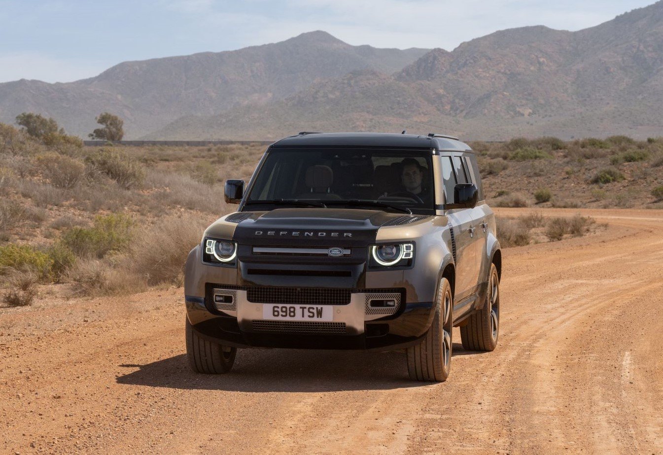 Land Rover Defender 130 driving on a desert dirt road, front view