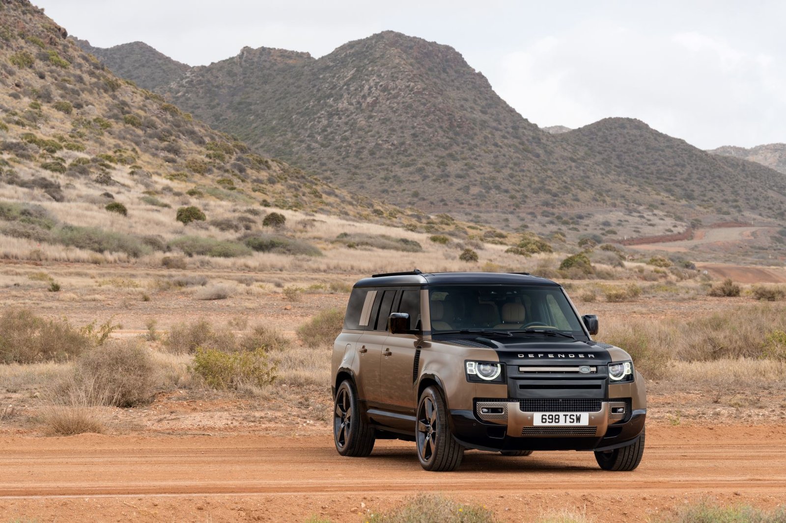 Land Rover Defender 130 parked on a dirt trail, front three-quarter view