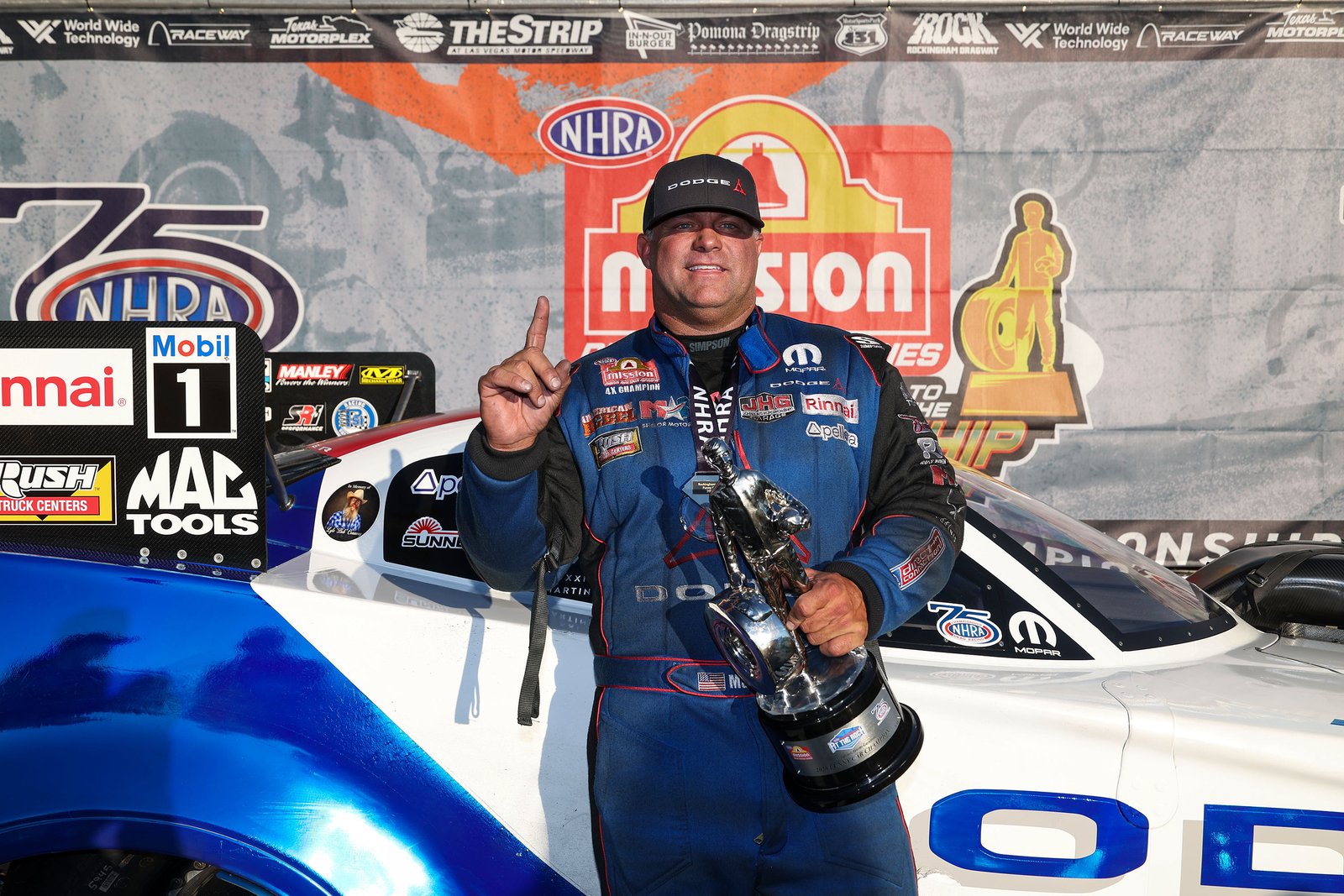 Matt Hagan holding the Wally trophy beside his Dodge Funny Car