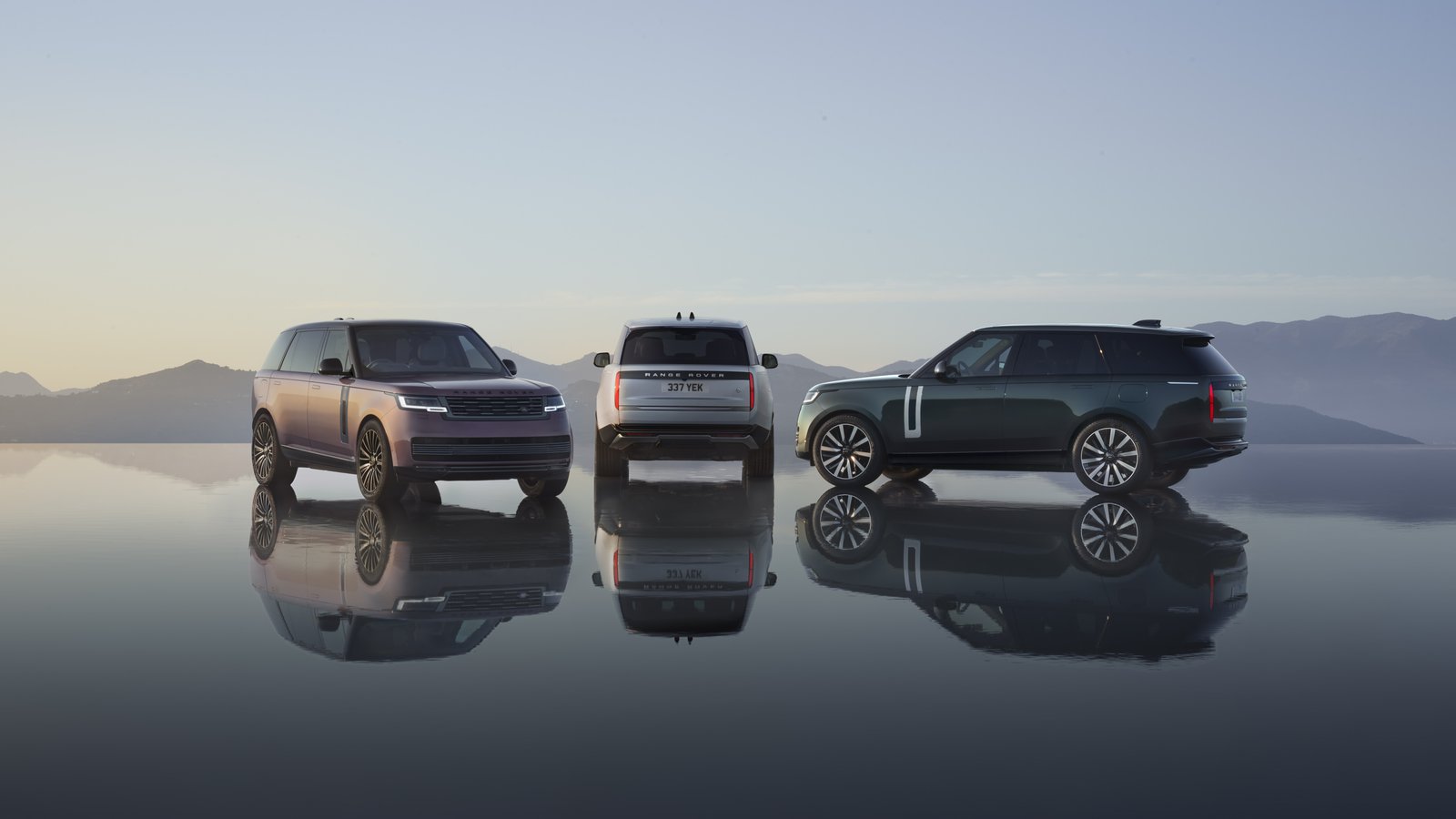 Three Range Rover Electric SUVs in different colors on reflective surface