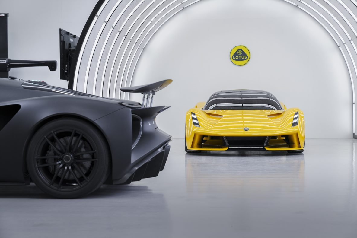 Yellow Lotus Evija front view in a studio beside a black Evija