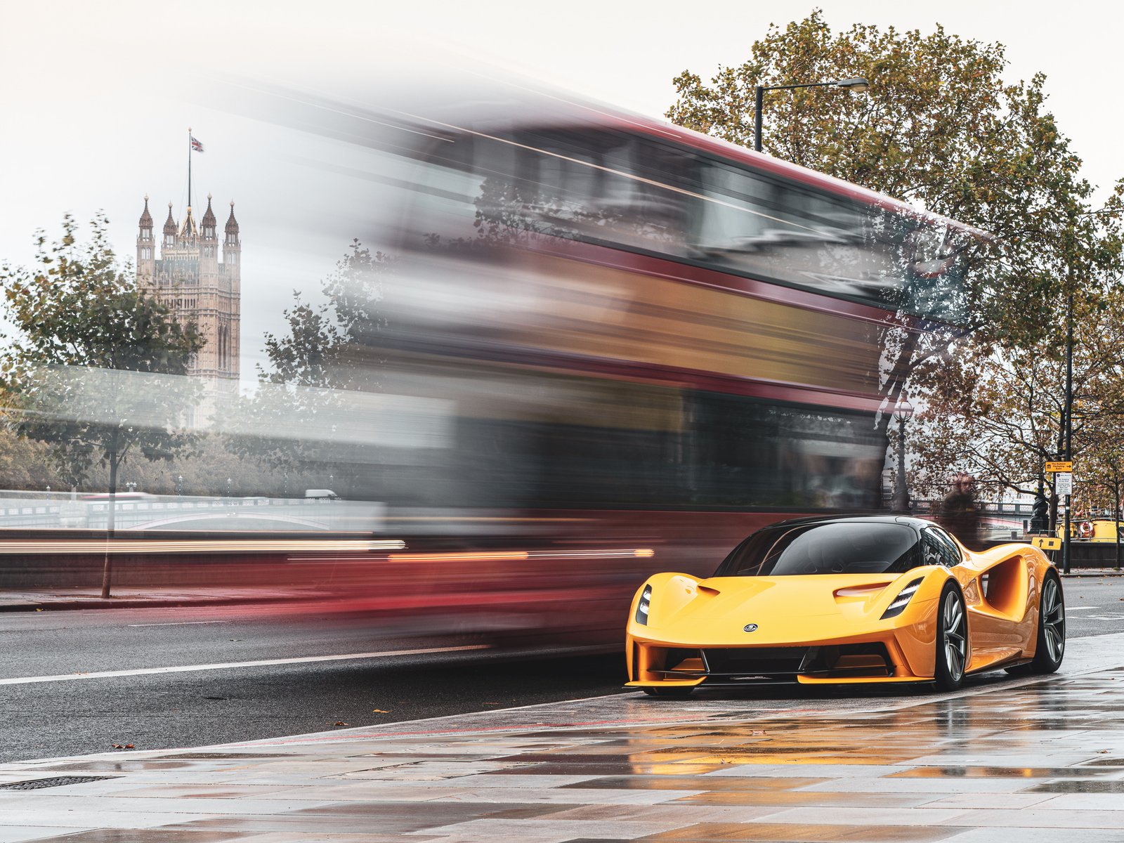 Yellow Lotus Evija parked near Westminster as a London bus passes