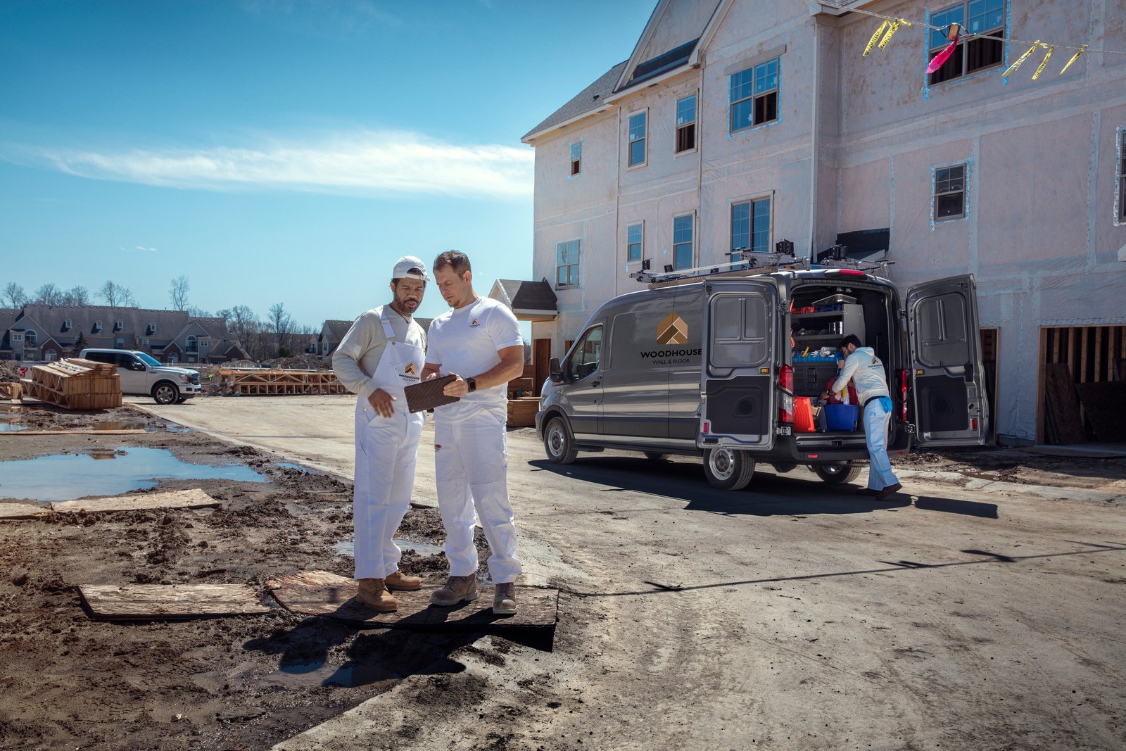 Contractors reviewing plans beside a Ford Transit van at a job site