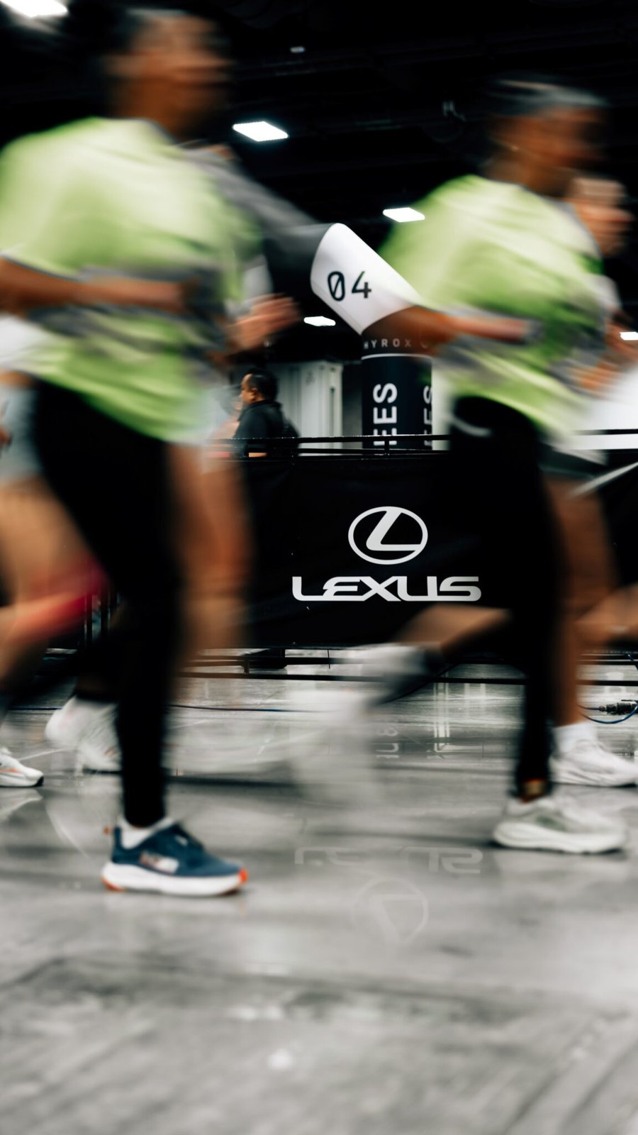 HYROX racers running past Lexus branding on course barrier