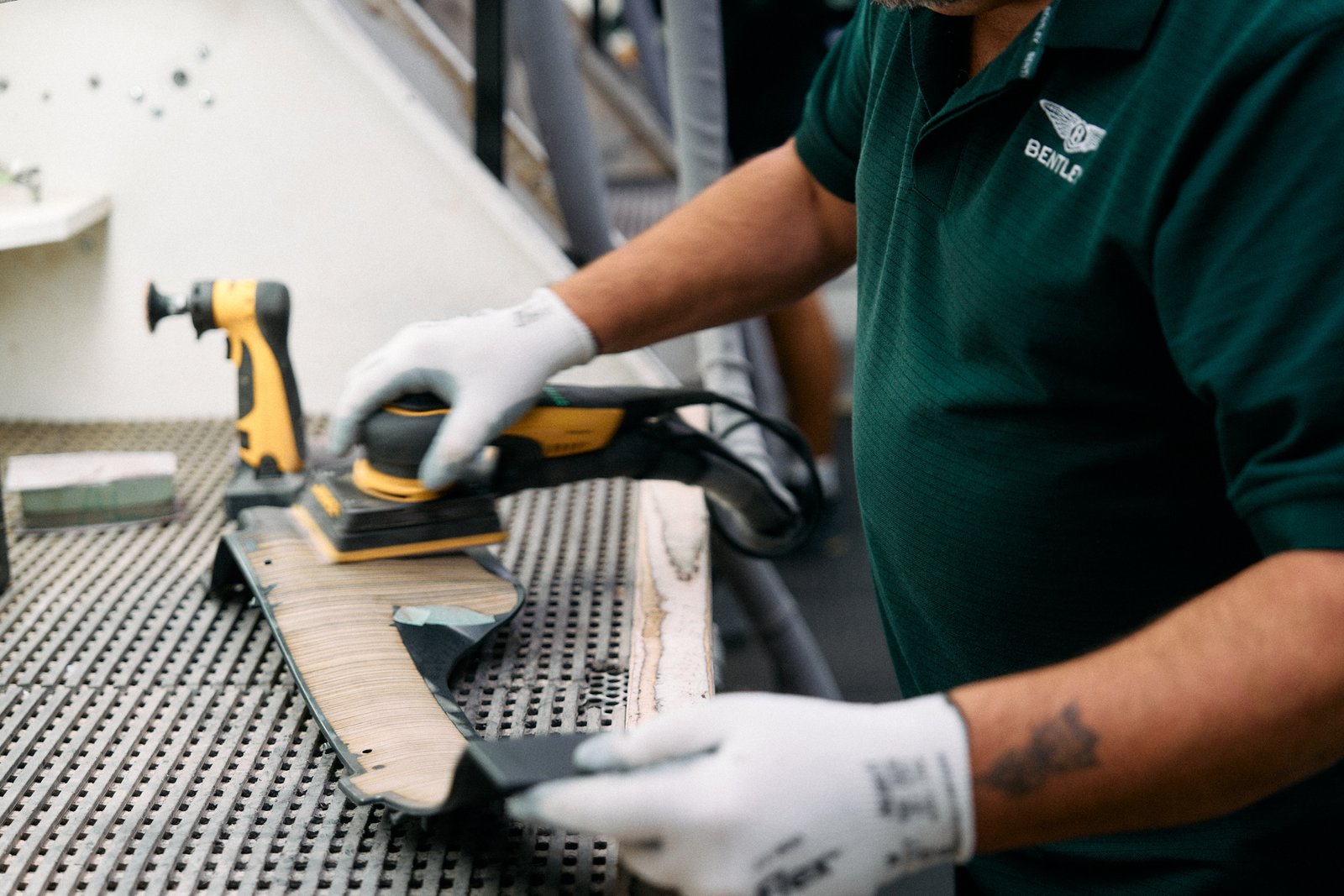 Bentley worker hand-sanding a wood veneer trim piece
