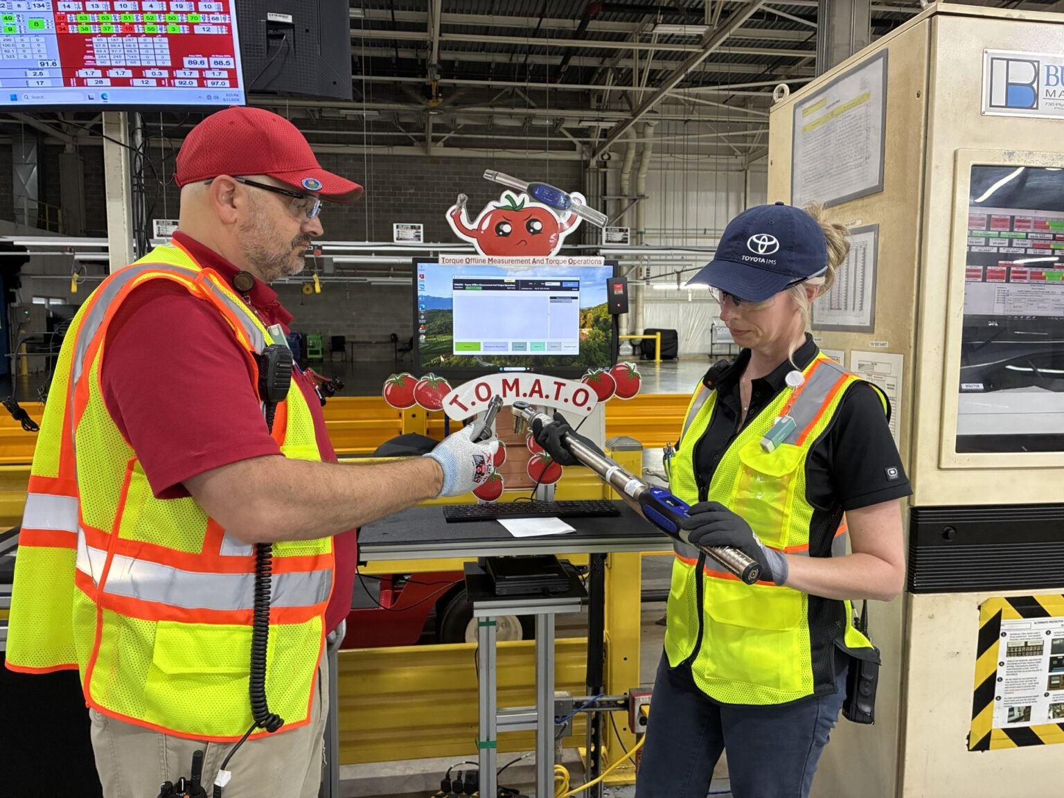 Two Toyota quality team members checking torque wrenches at a test station