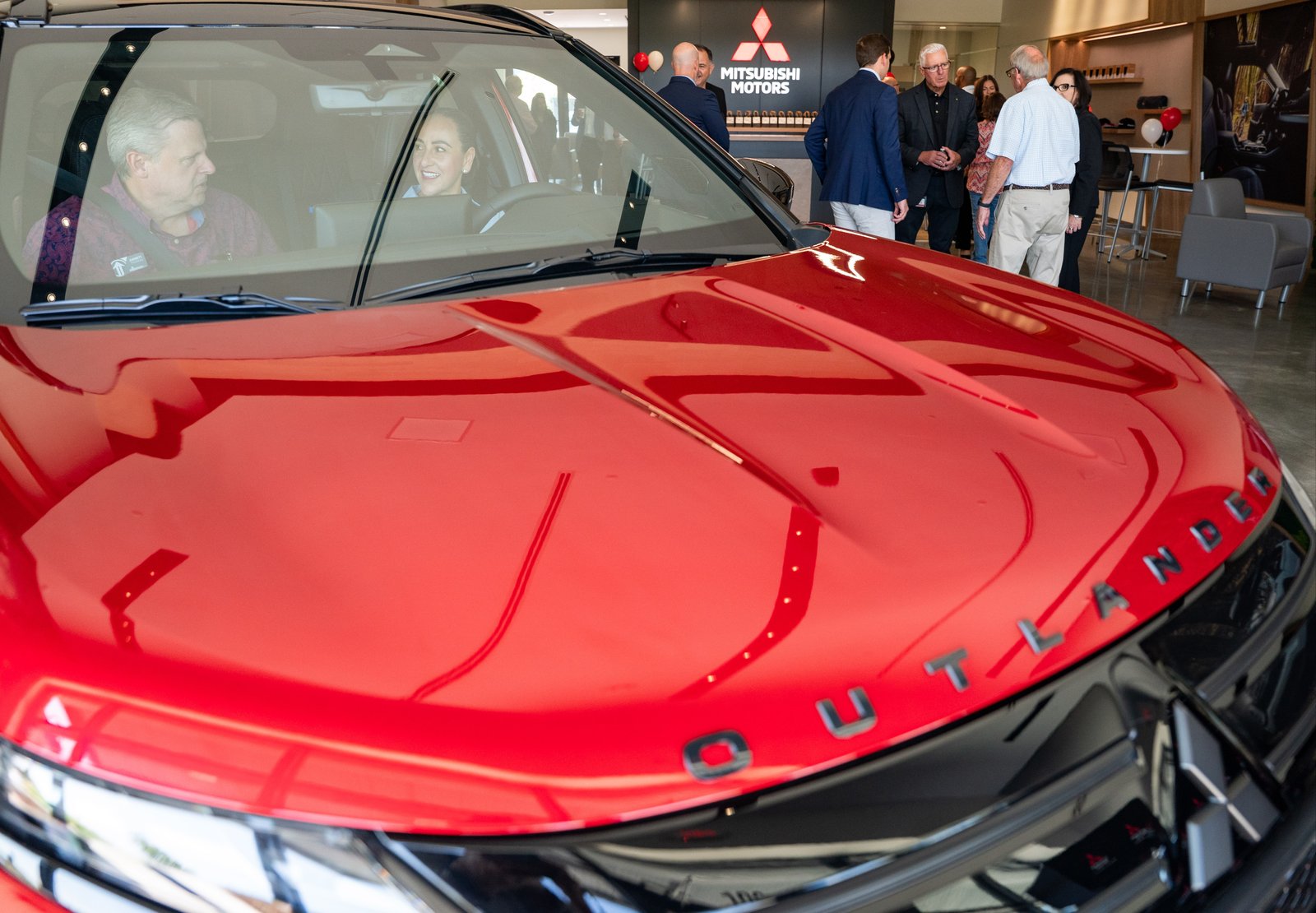 Visitors sitting inside a red Mitsubishi Outlander at the Gallery showroom