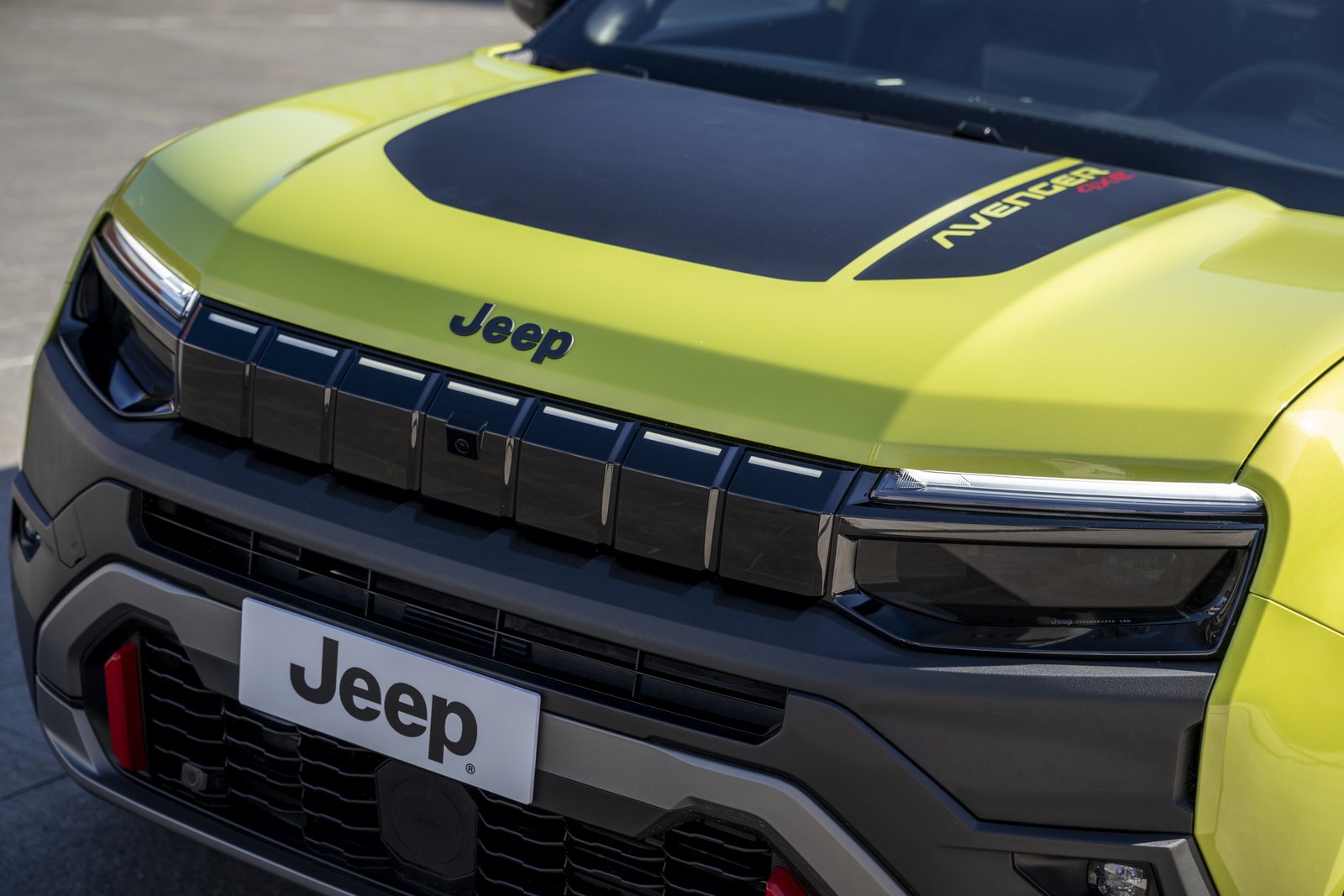 Close-up of the Jeep Avenger's illuminated seven-slot grille and LED headlights