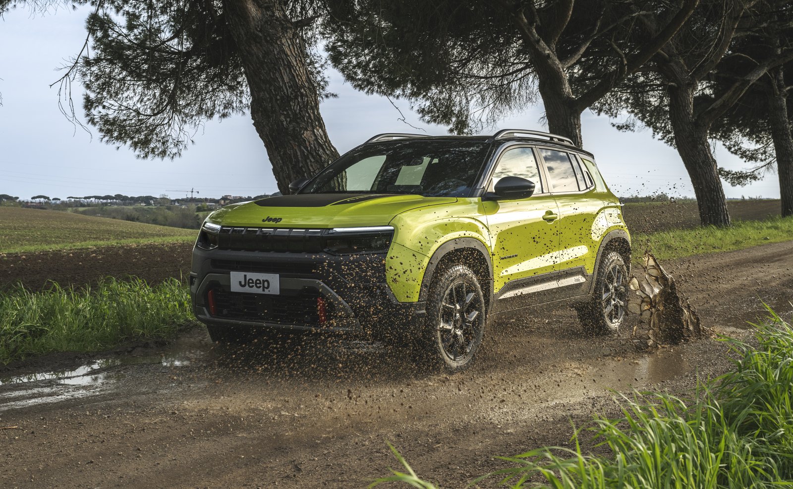 Jeep Avenger 4xe splashing through mud on a dirt road