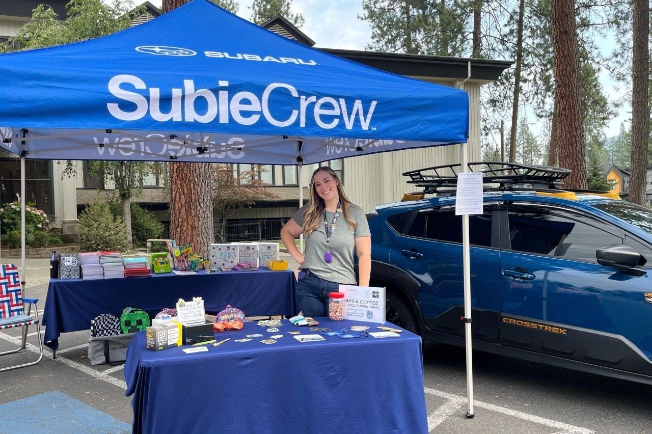 SubieCrew tent at a Cars & Coffee school supply drive beside a Crosstrek