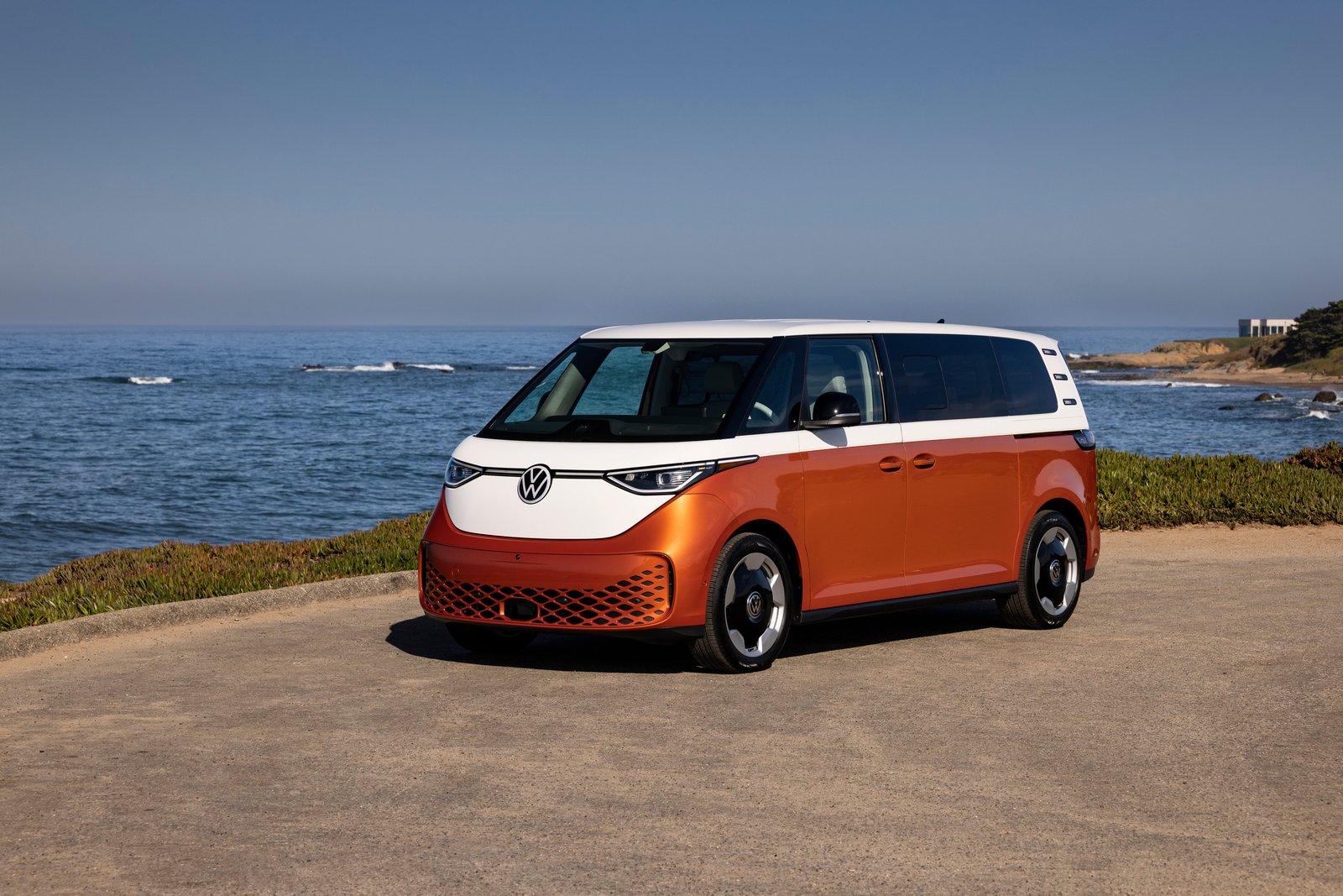 Orange and white Volkswagen ID. Buzz parked on a coastal overlook