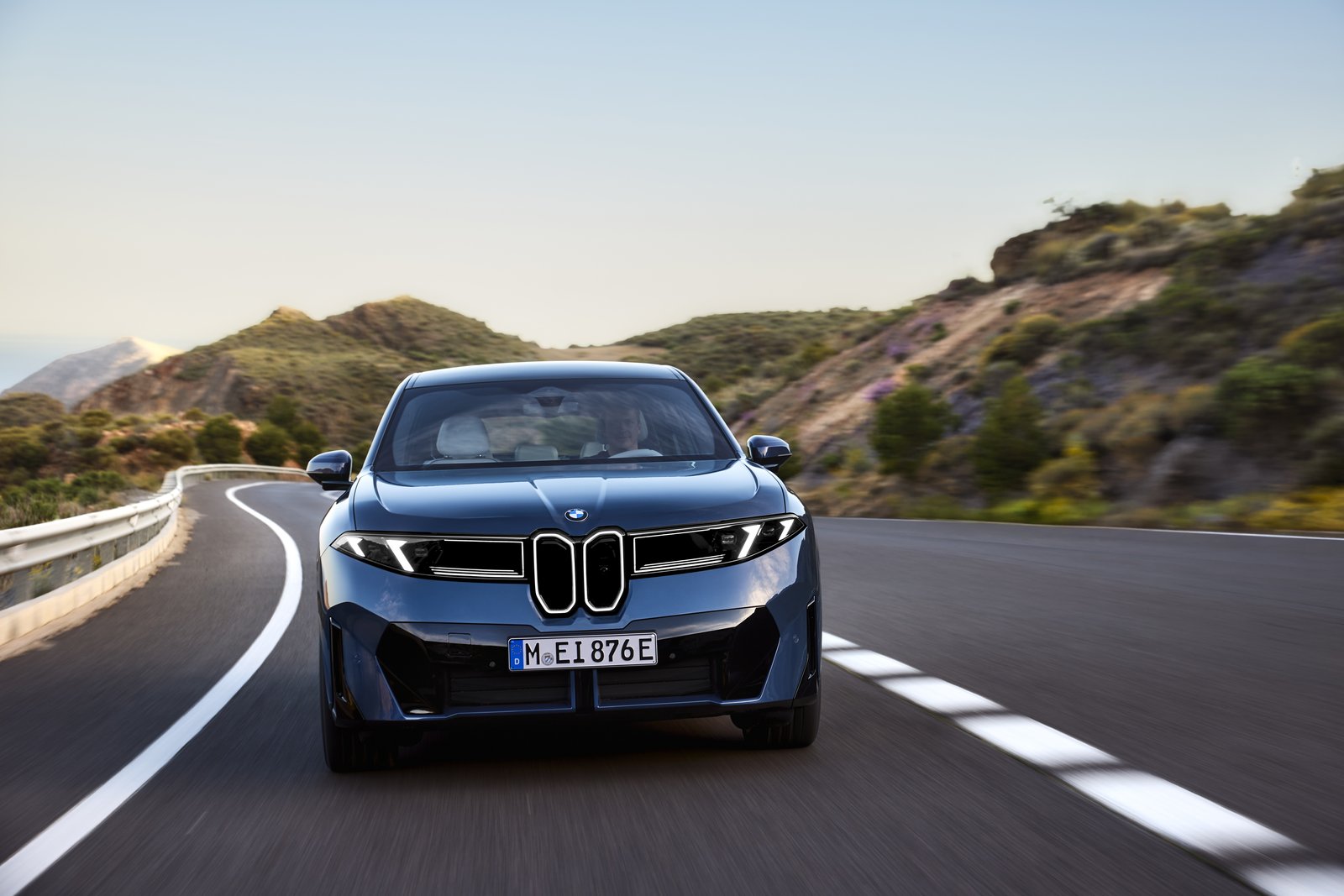 Blue BMW iX3 electric SUV front view on a mountain road