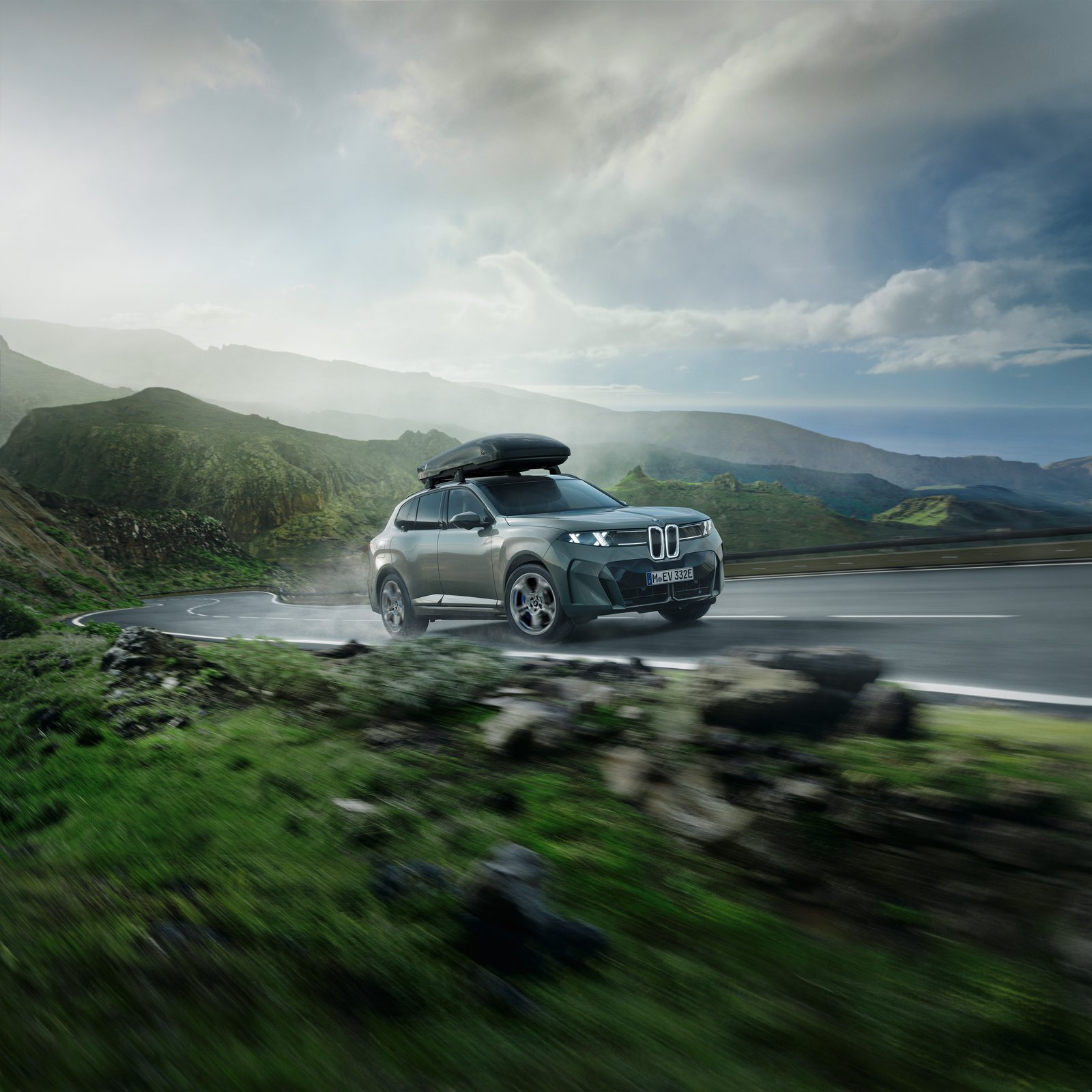 BMW iX5 driving mountain road with Aero roof box