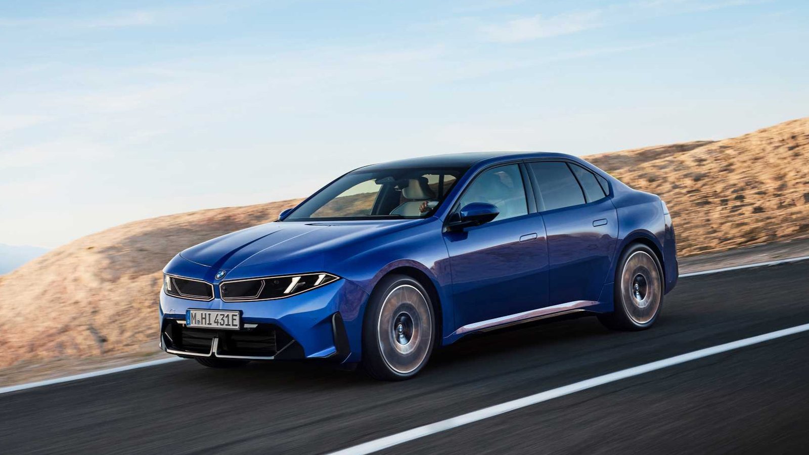 Blue BMW i3 50 xDrive electric sedan driving on a coastal road