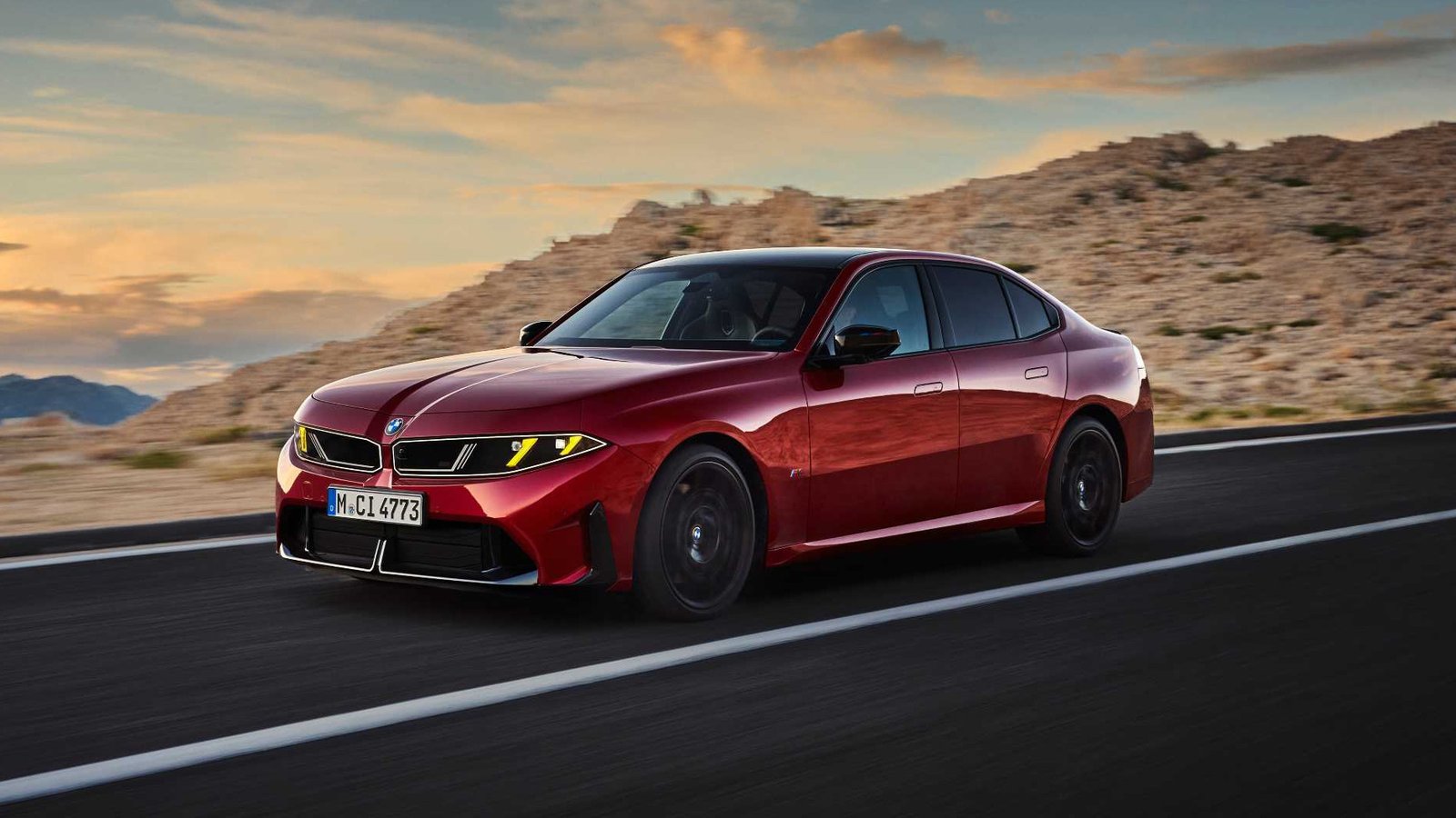 Red BMW M350 xDrive driving on a desert road at sunset
