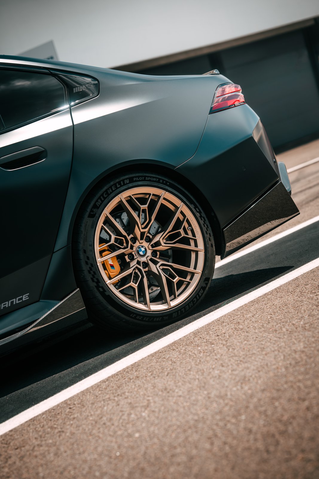 Rear Gold Bronze M Performance wheel on a BMW M5 at a racetrack
