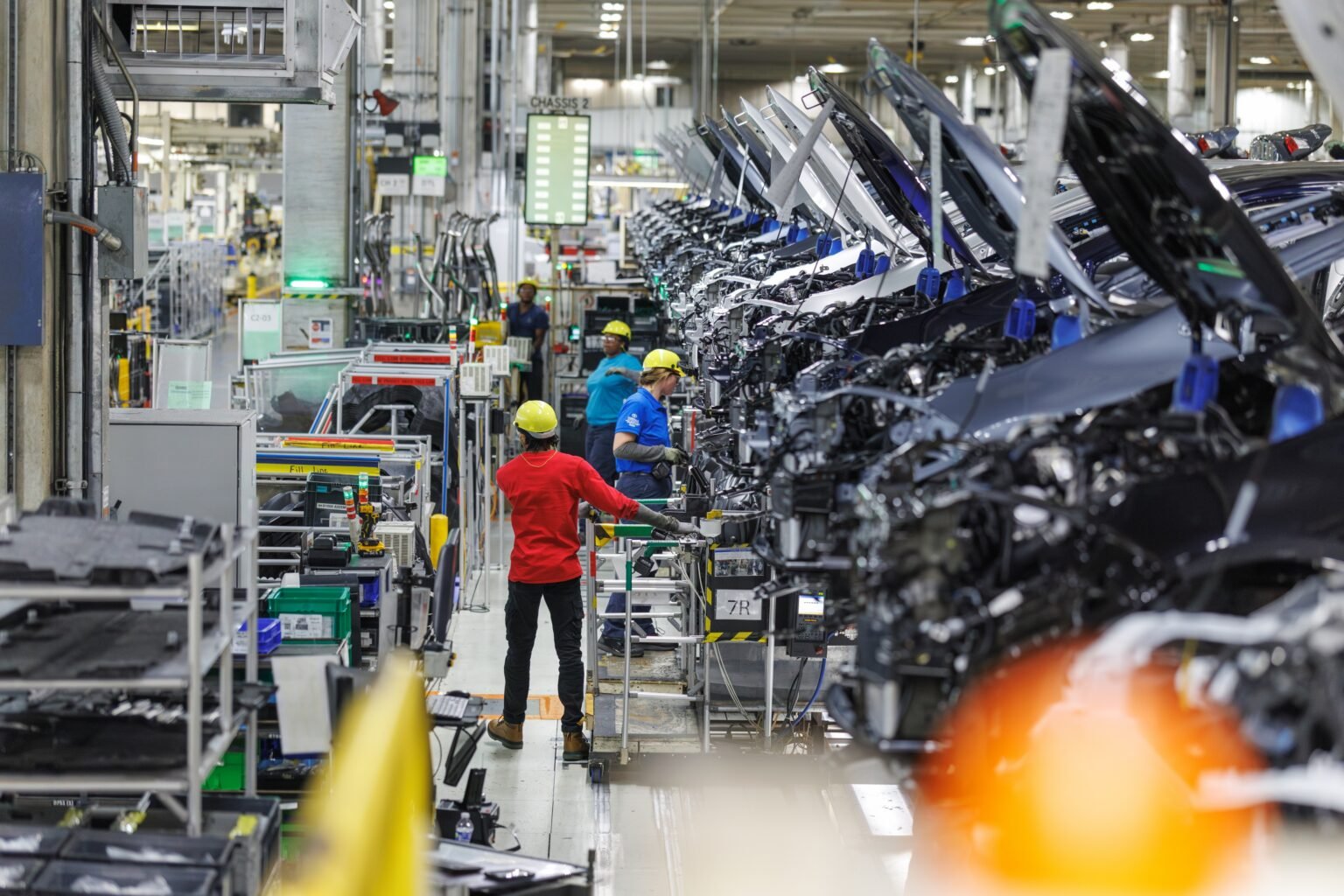 Toyota workers installing components on Corolla bodies along a chassis line