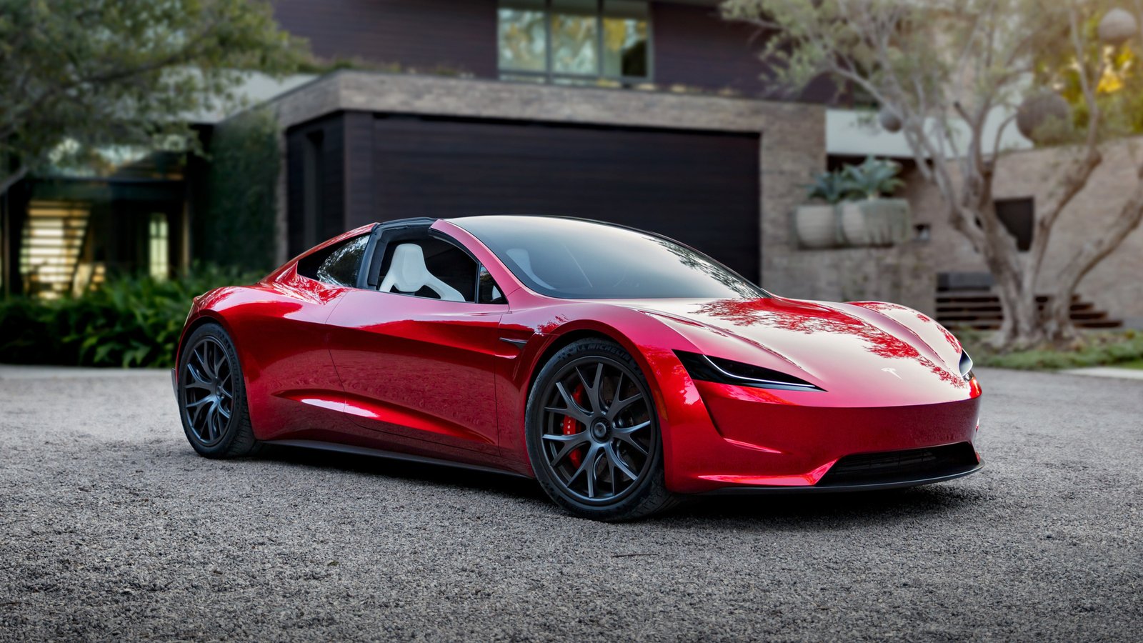 Red Tesla Roadster prototype parked in a gravel driveway