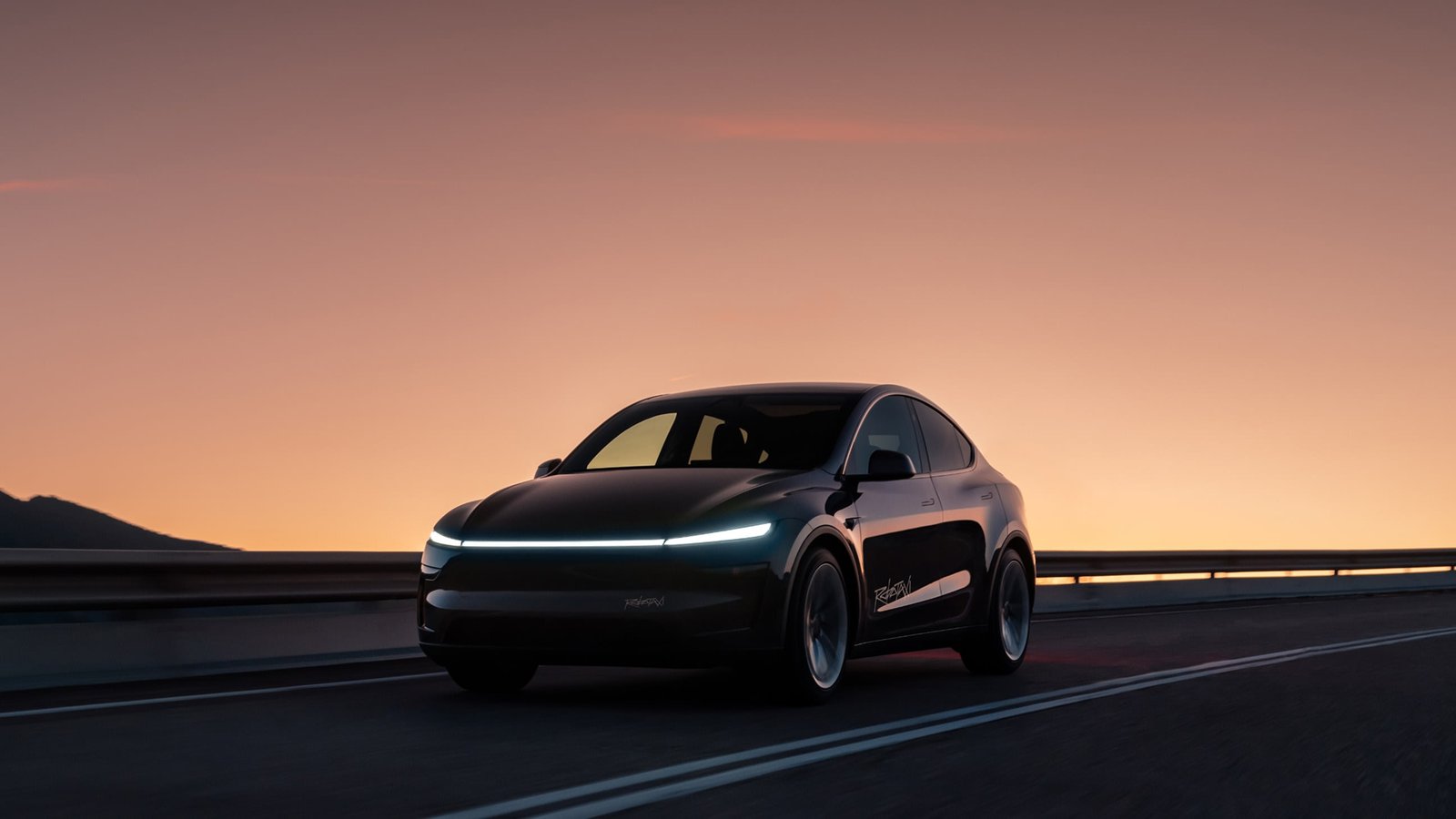Black Tesla Model Y Robotaxi driving at dusk