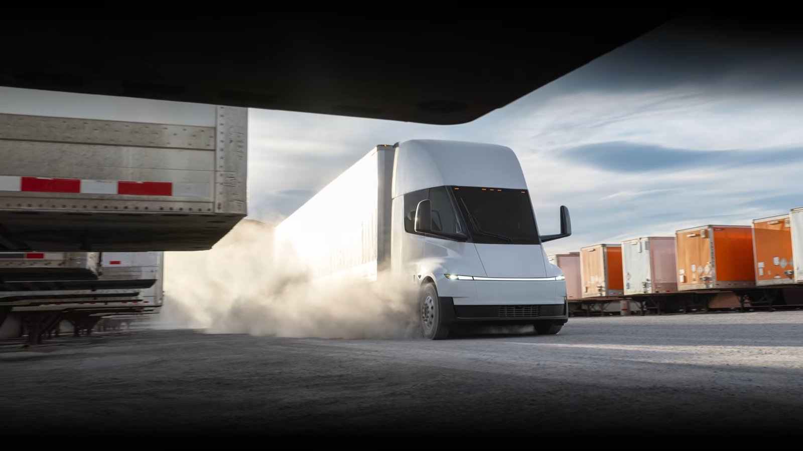 Tesla Semi pulling out of a freight yard between parked trailers