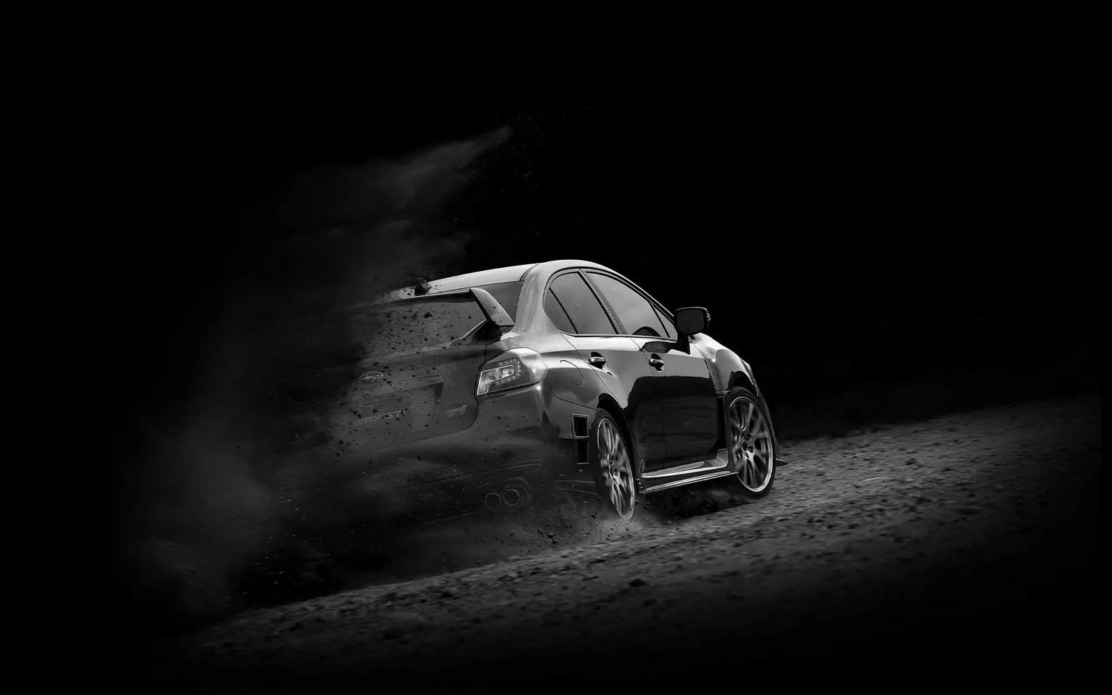 Previous-generation Subaru WRX STI kicking up gravel in black and white