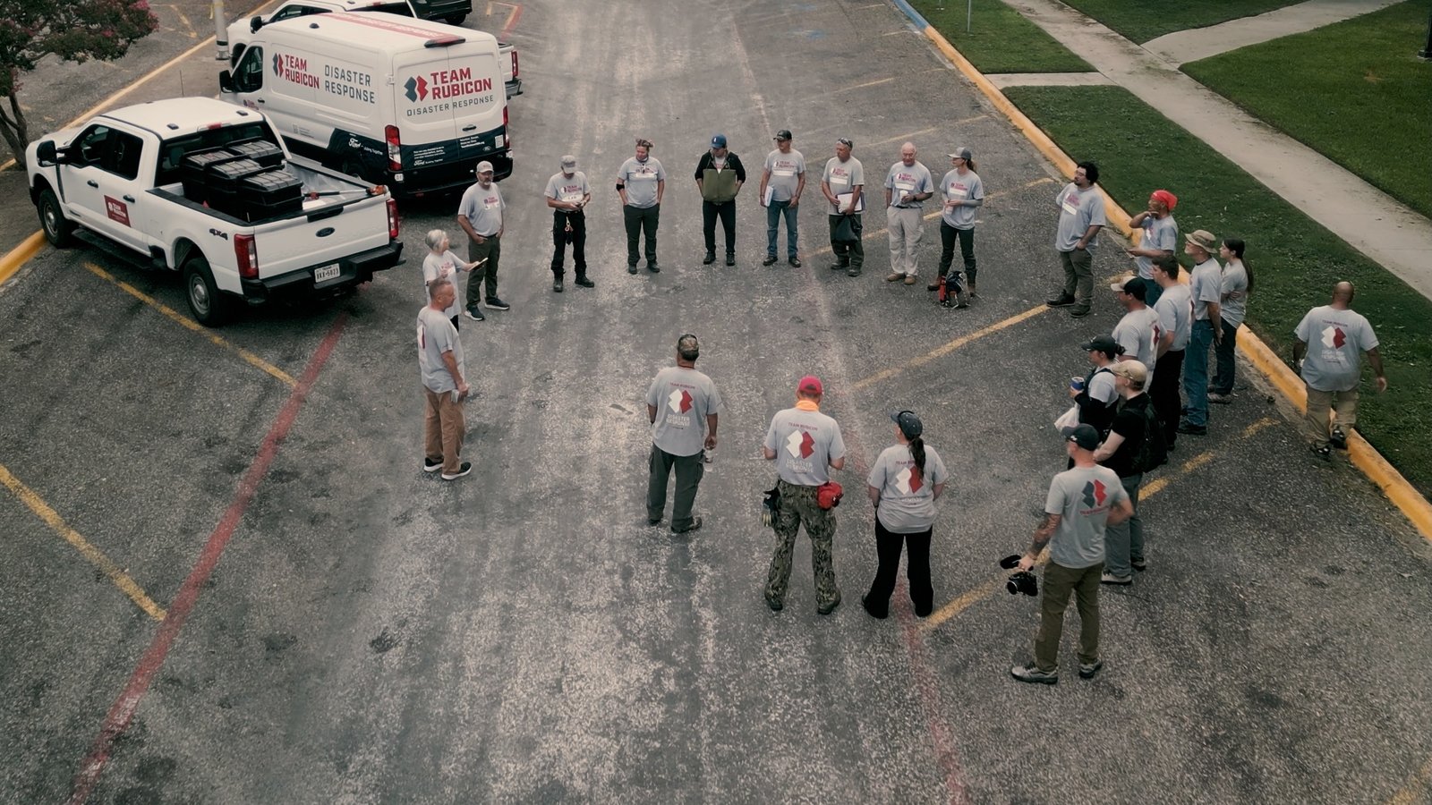 Team Rubicon volunteers briefing beside Ford Transit and Super Duty trucks